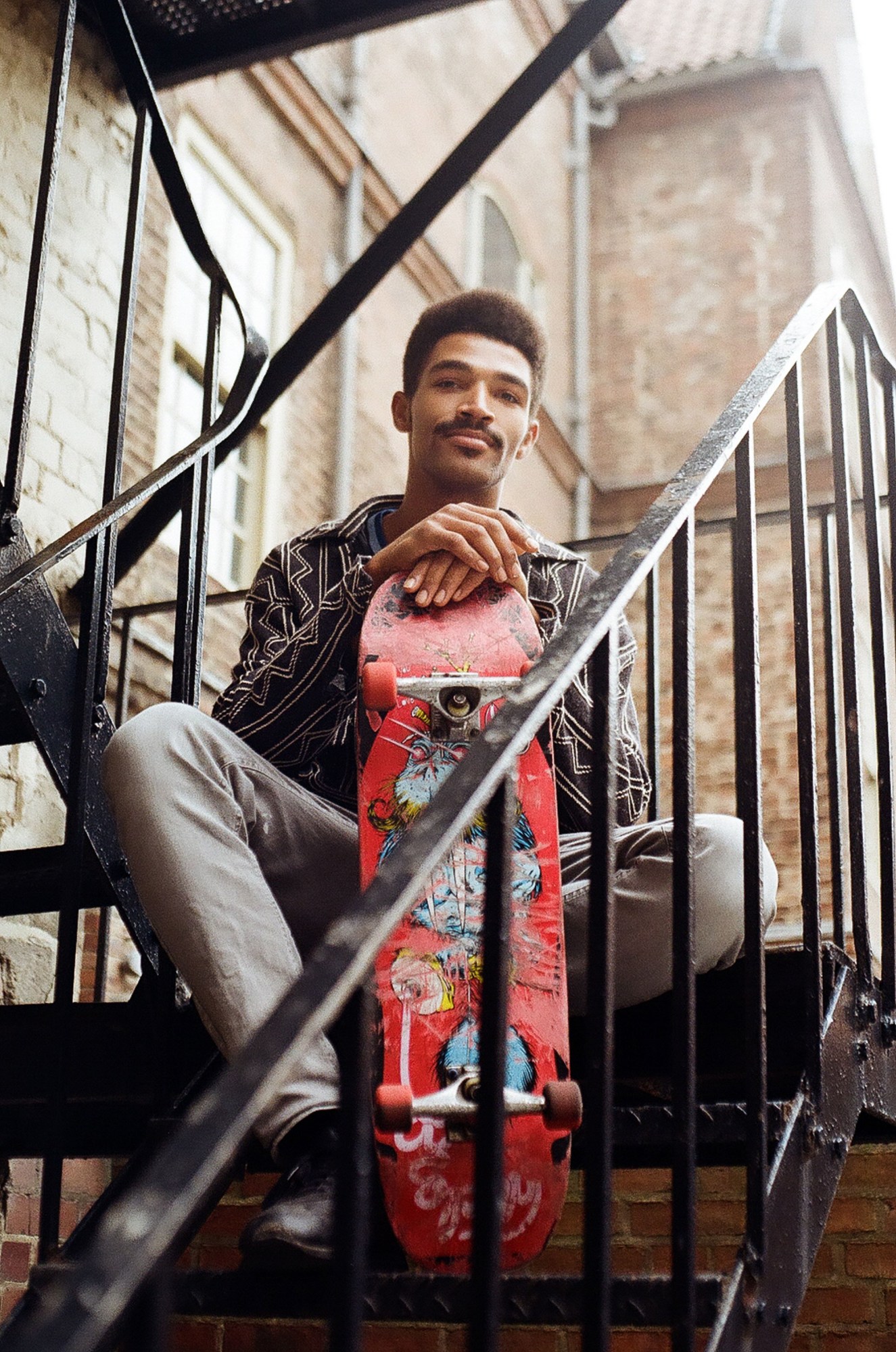 Newcastle youth photography: a man sitting on a fire escape with a skateboard