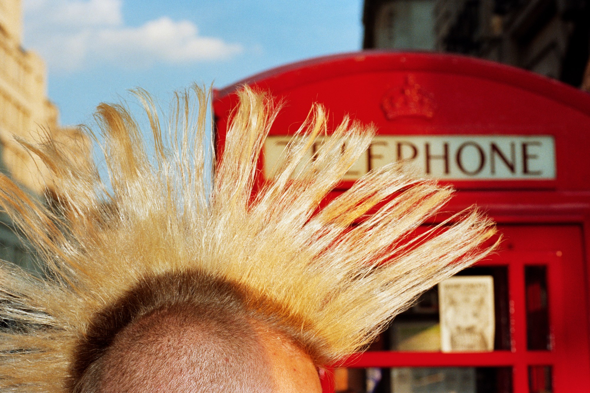 Martin Parr photographs a mohawk in front of a red telephone box