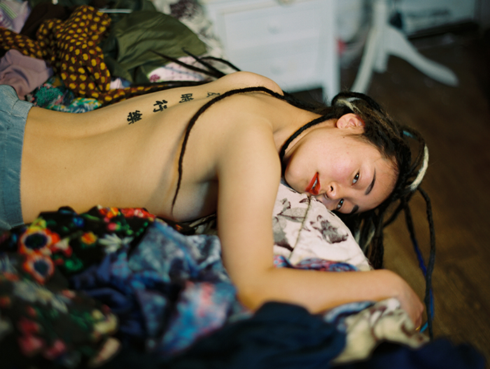 luo yang photographs a topless girl lying on a bed