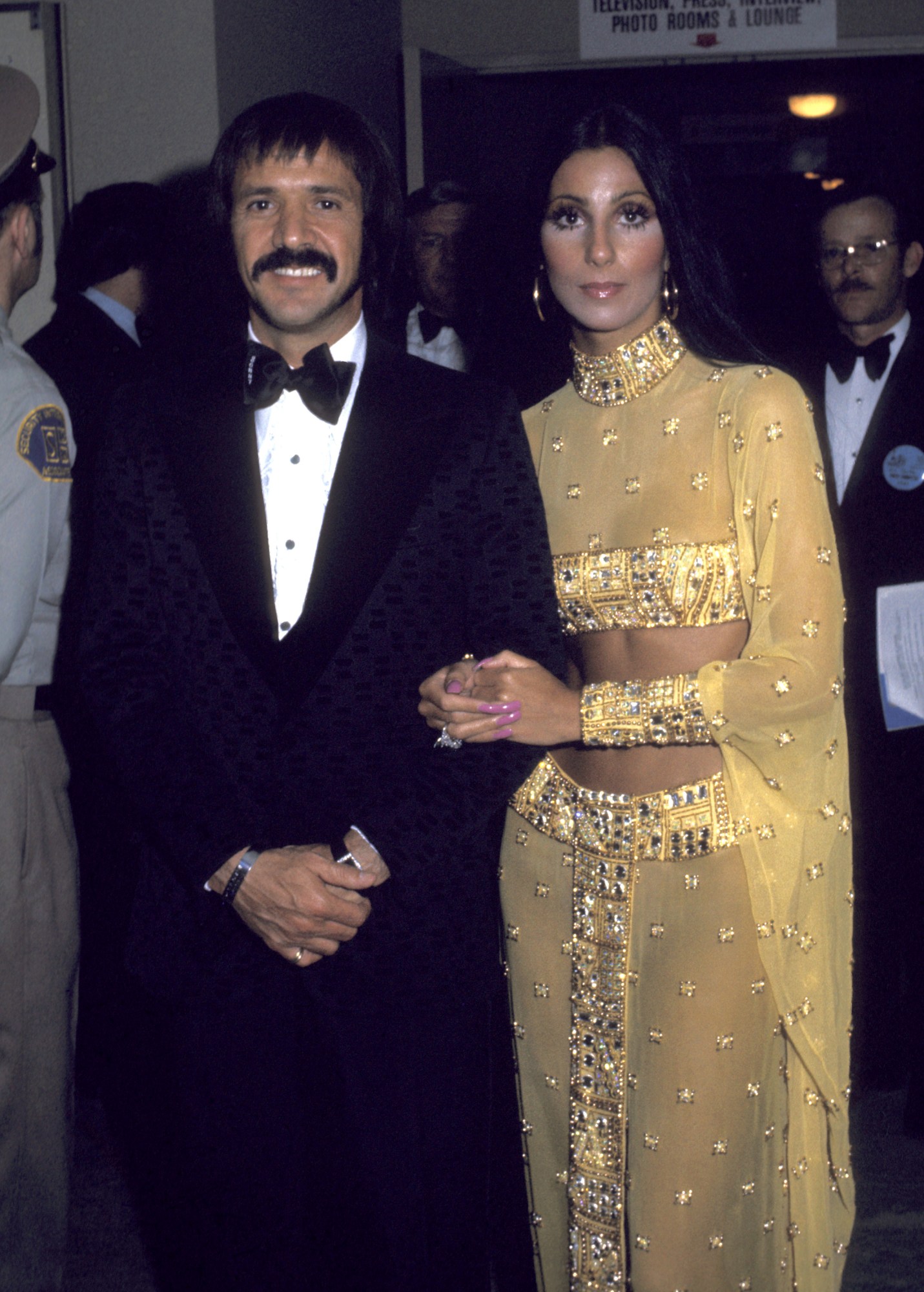 sonny and cher arm and arm at the academy awards in a gold sequin dress