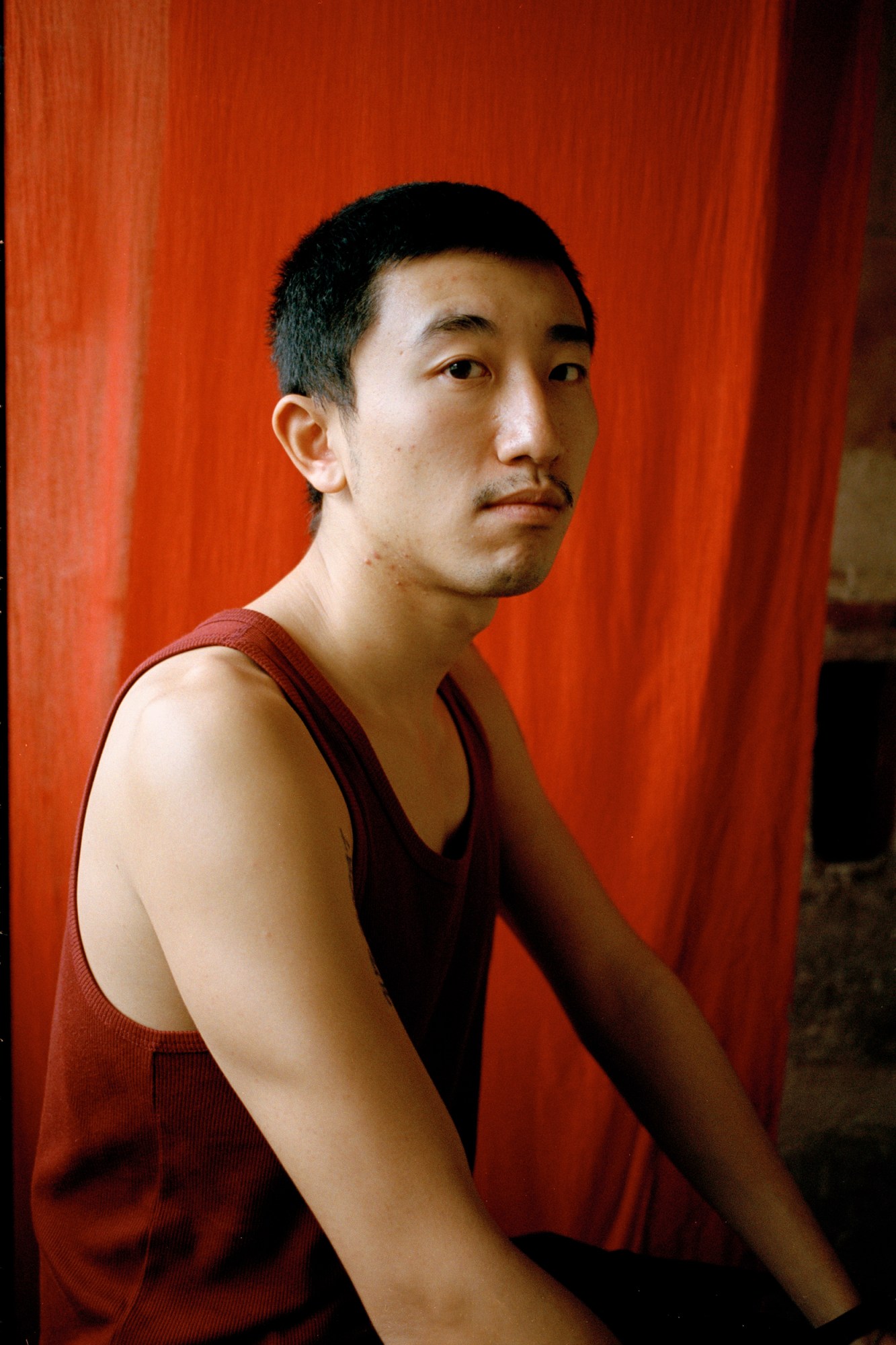 a man in a tank top looks into the camera by celine yasemen