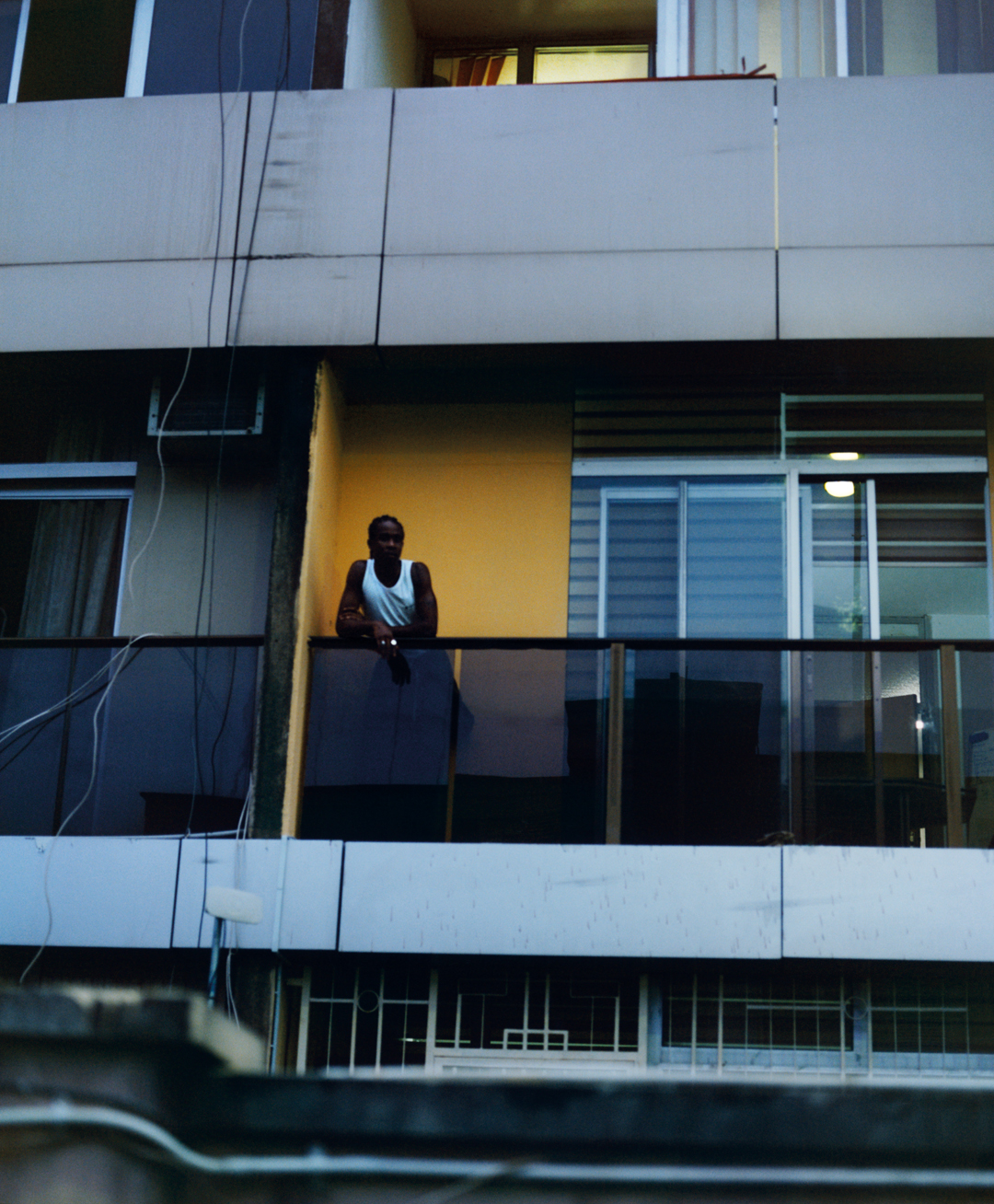 Man looks out of window in apartment block