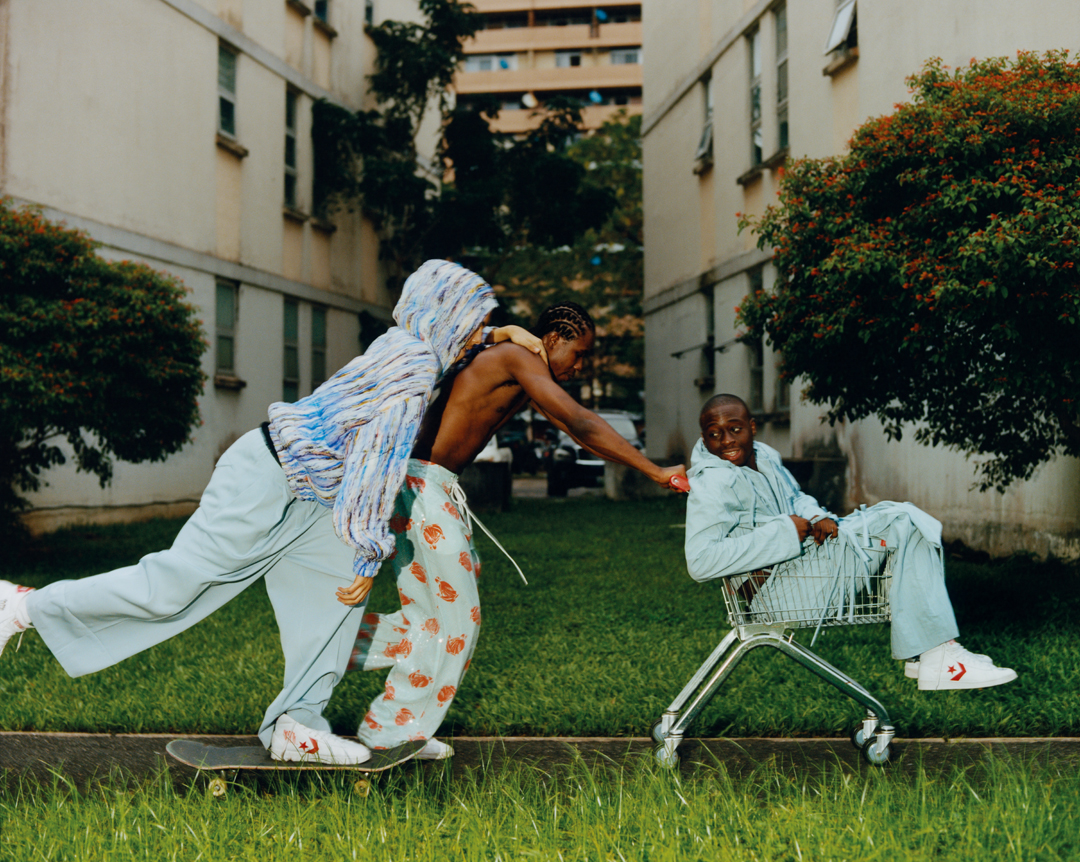 Skaters run through grass, one of them in a trolley