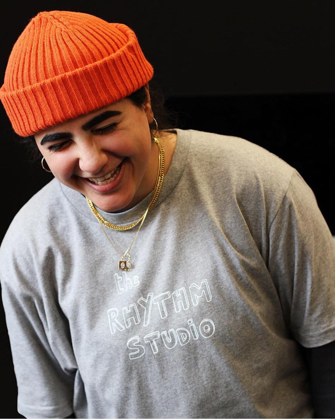 Shamine in grey T-shirt and orange wool hat