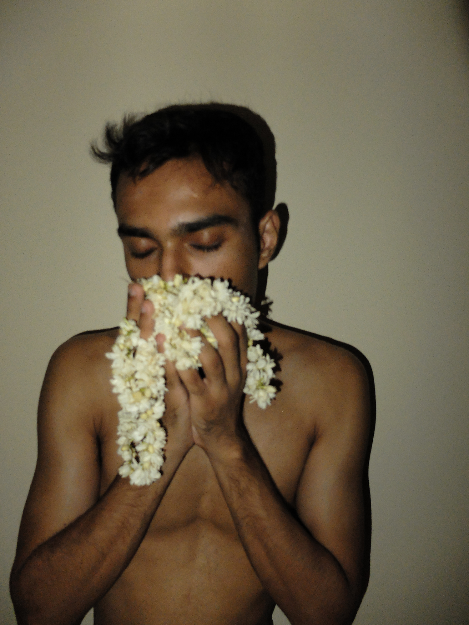 Nude man sniffs a bouquet of white flowers