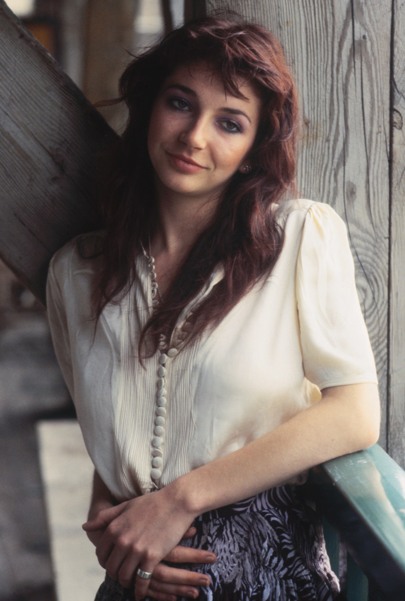 Kate Bush wearing a white blouse and animal print skirt in 1985.