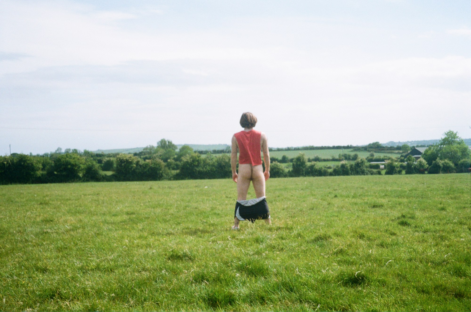 Image of a man shot from behind in green field