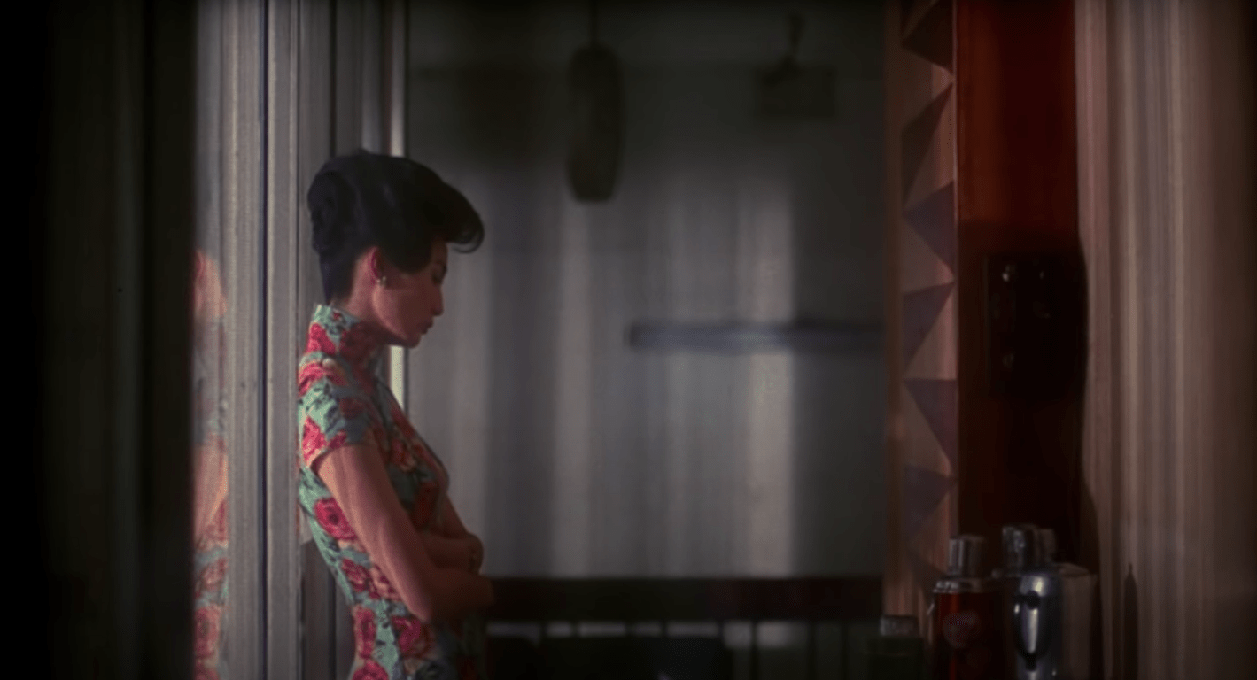 Maggie Cheung leaning pensively against a wall