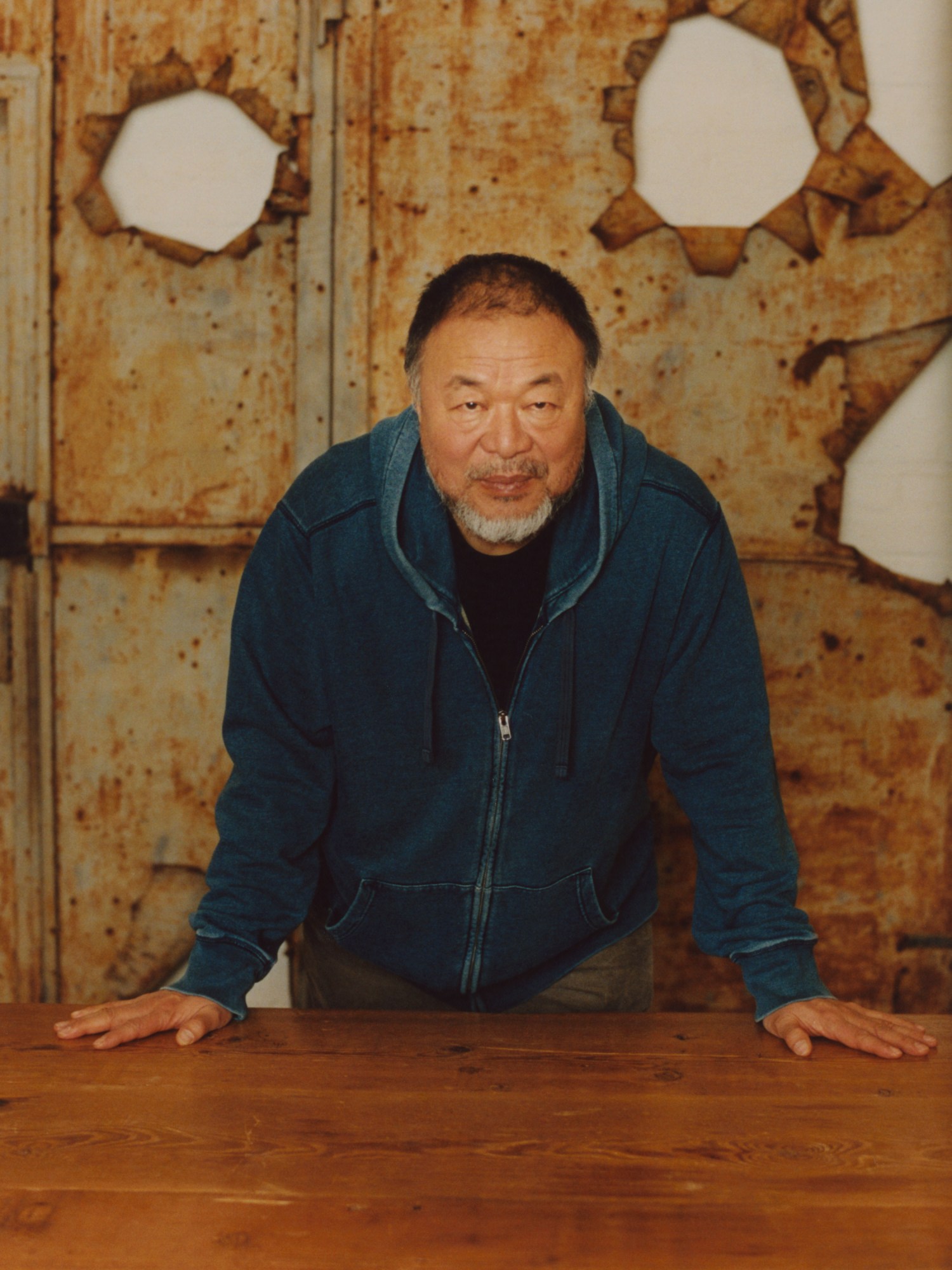 Ai Weiwei standing over a wooden table