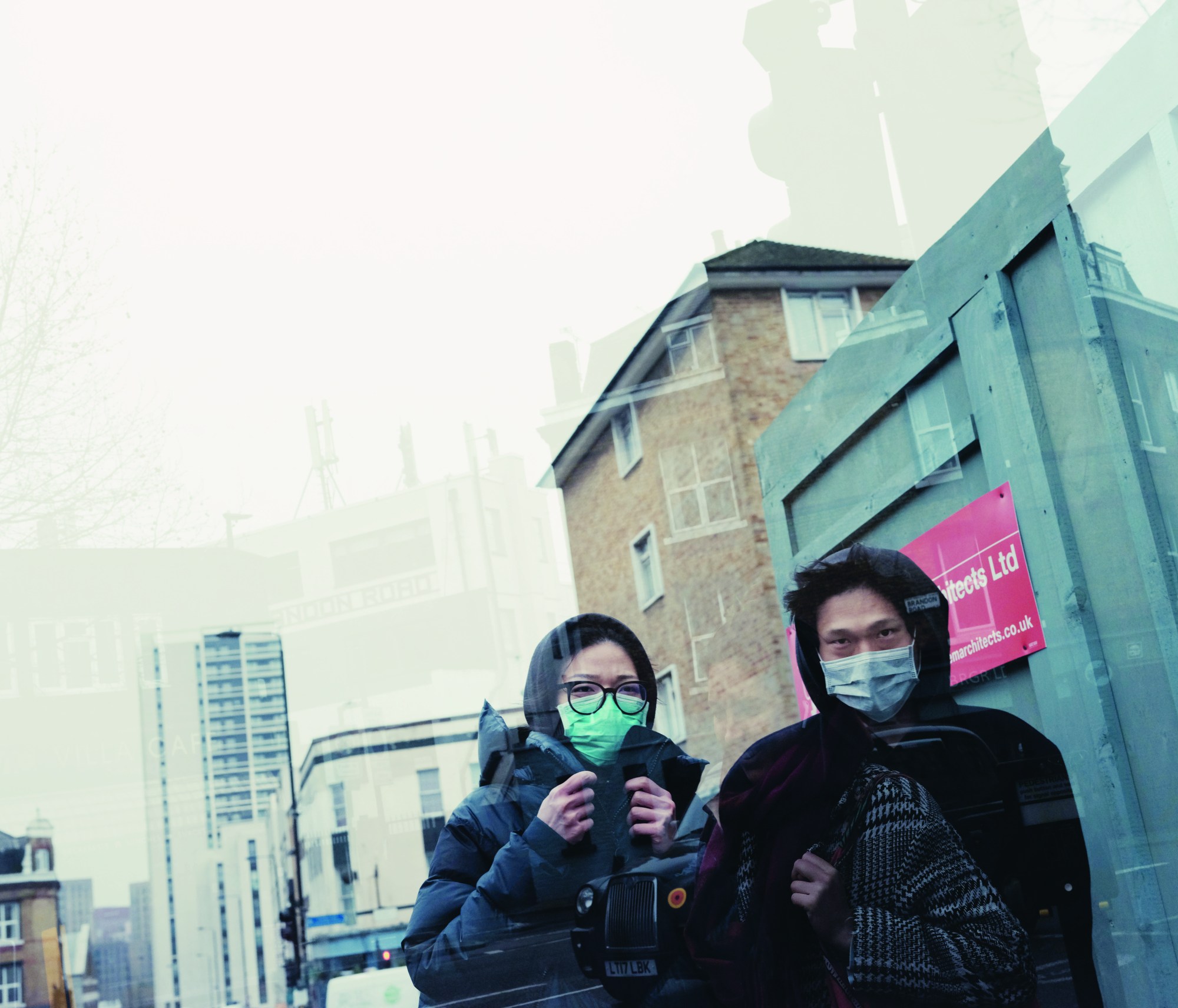 two people walking down a street in london with face masks