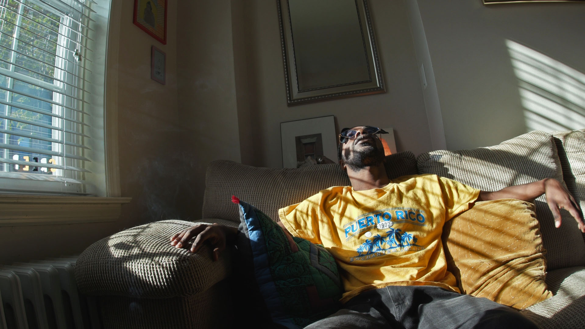 film still of man sitting on couch