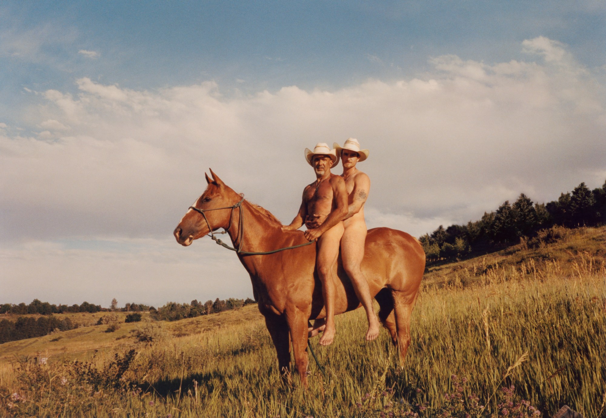 two men on top of a horse naked