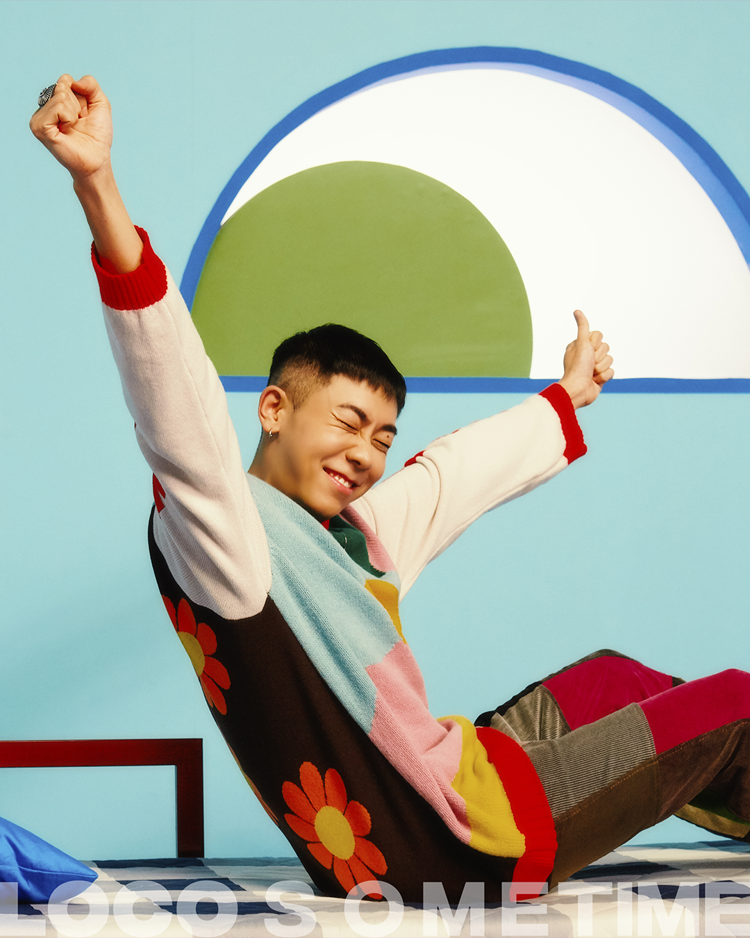 colourful photograph of korean musician loco sitting on a futon