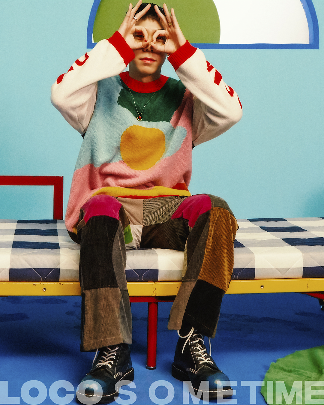 colourful photograph of korean musician loco sitting on a futon