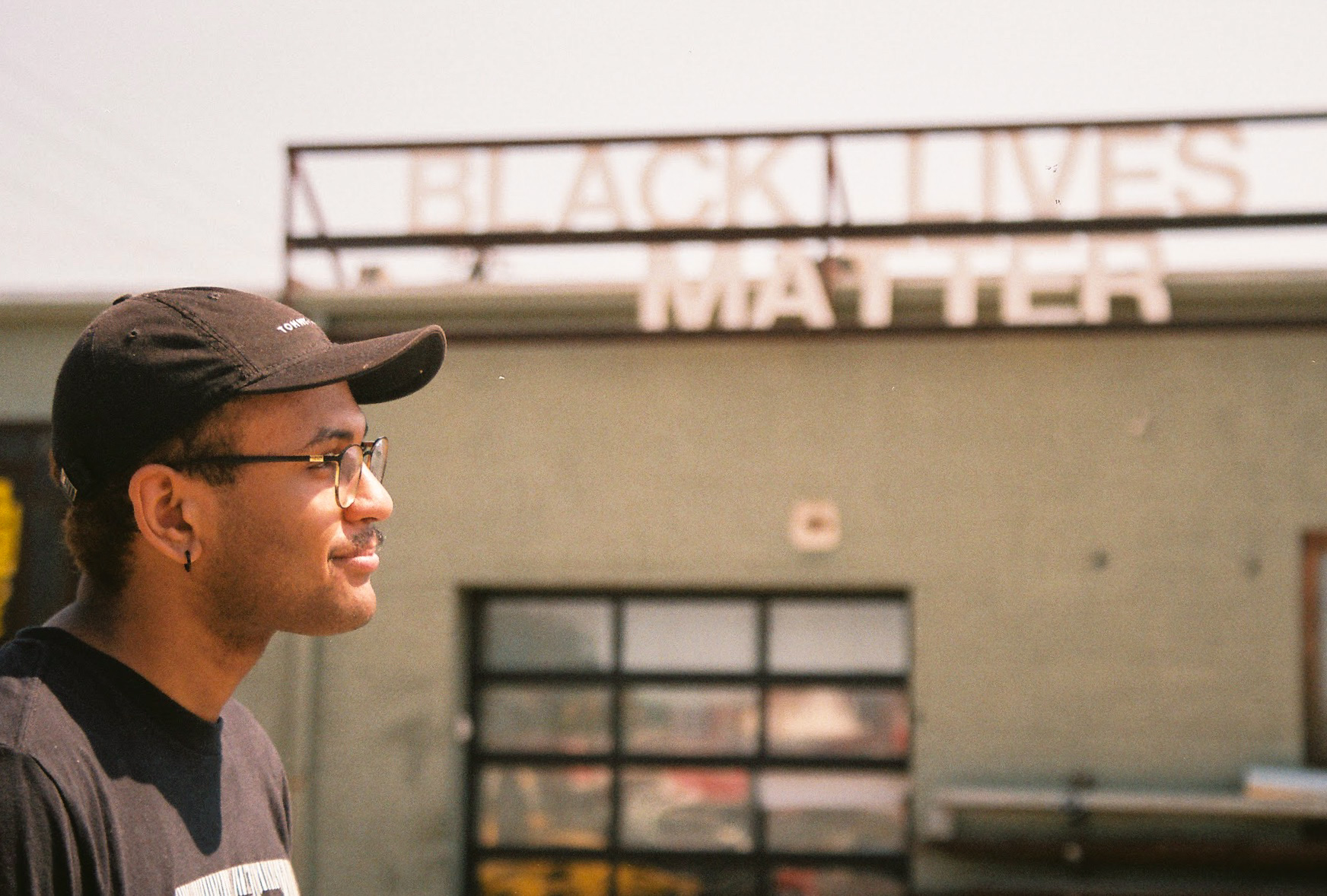 a man standing in front of a black lives matter sign