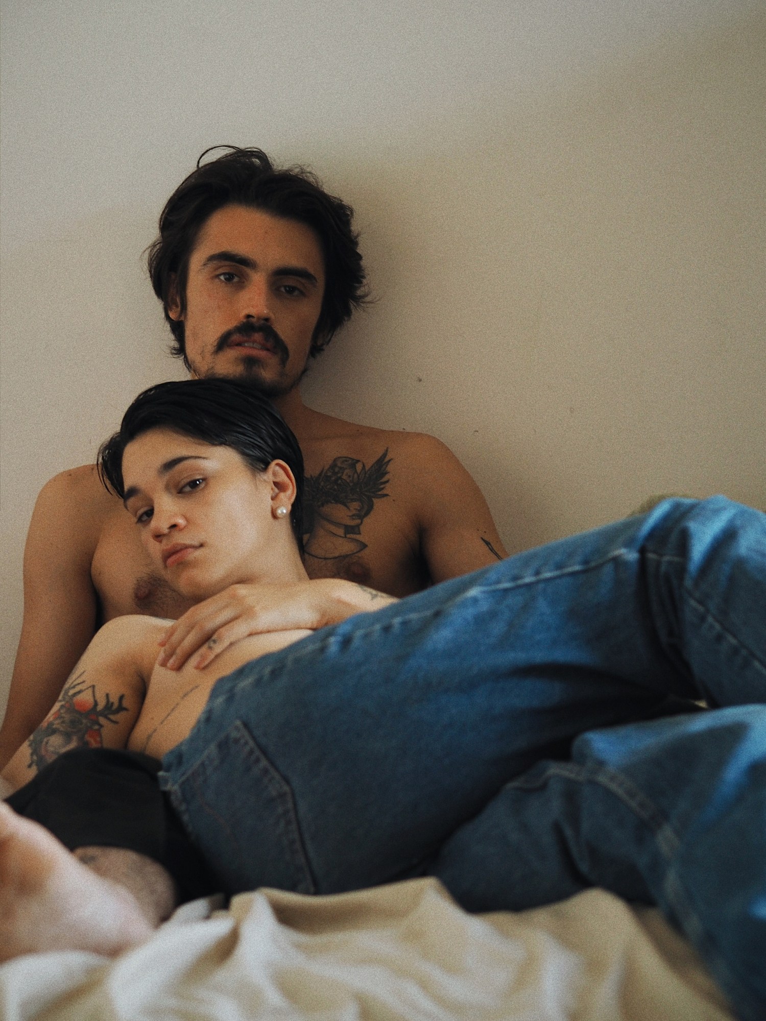 topless couple lying on a bed