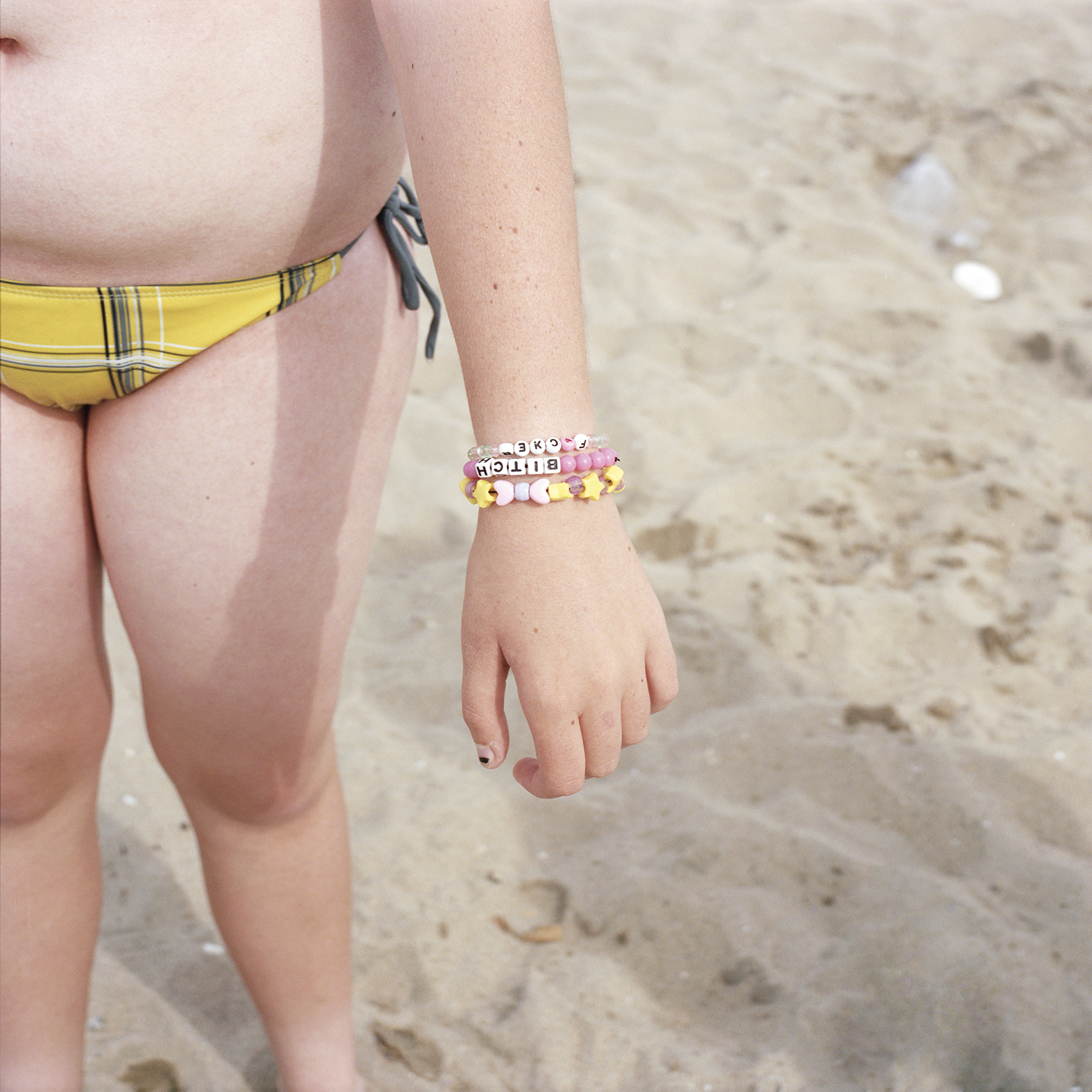 a child's wrist wearing a bracelet that says bitch by deanna templeton