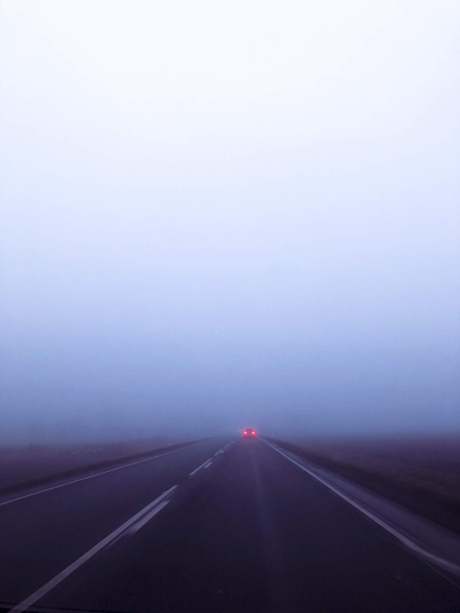 a car ahead on a long foggy road