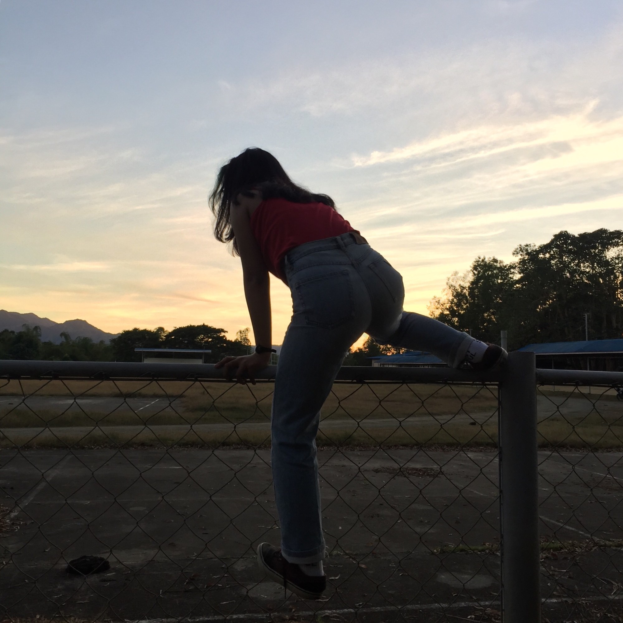 a girl climbing over a fence