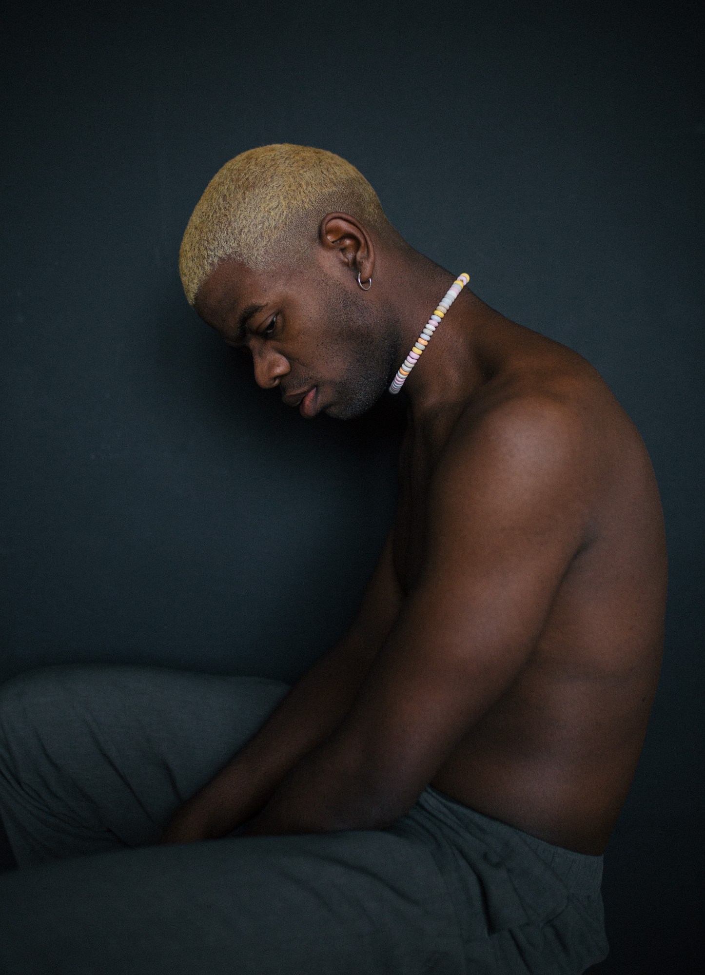 a shirtless man with blonde hair and a candy necklace