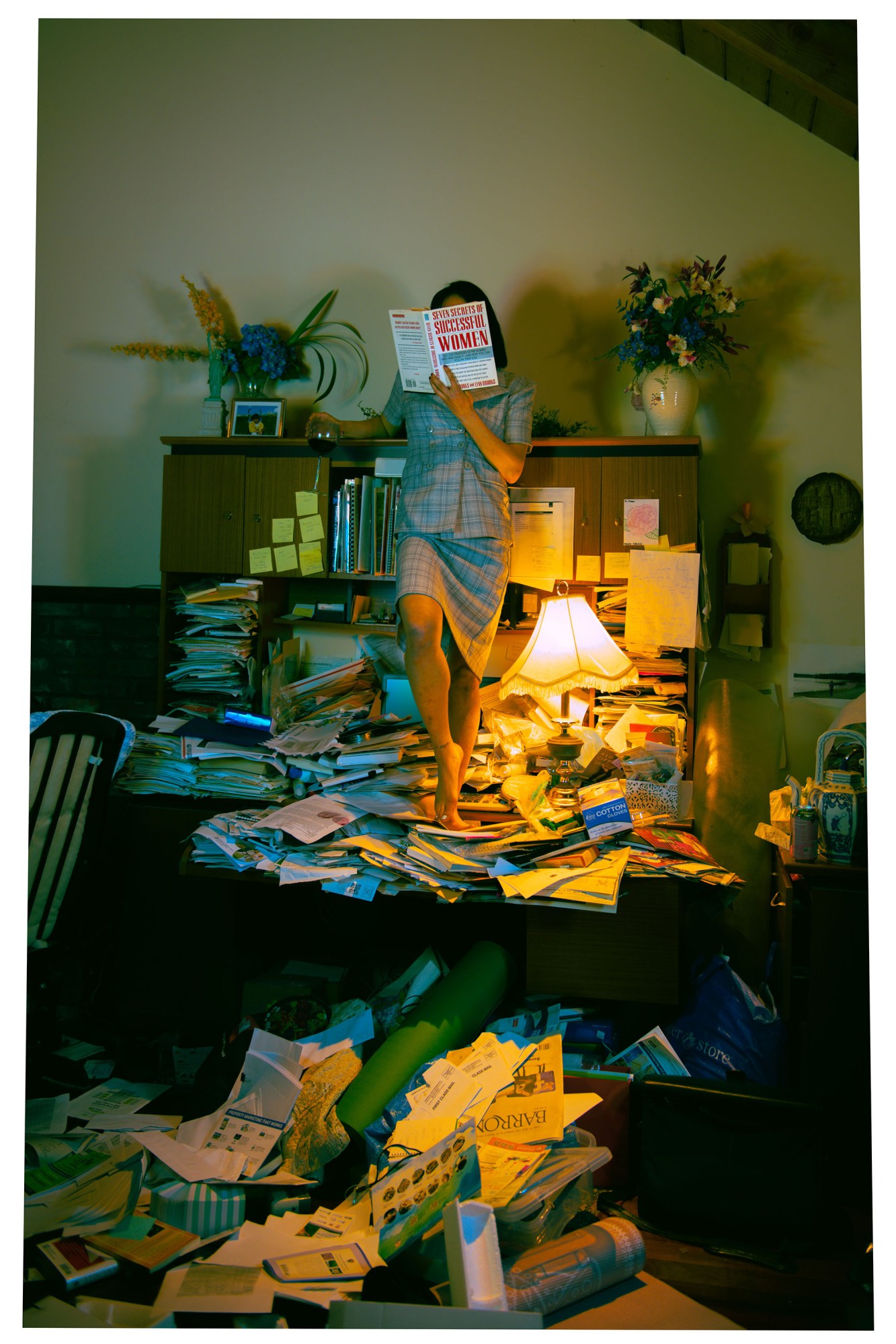 a woman standing on a desk covered in paper