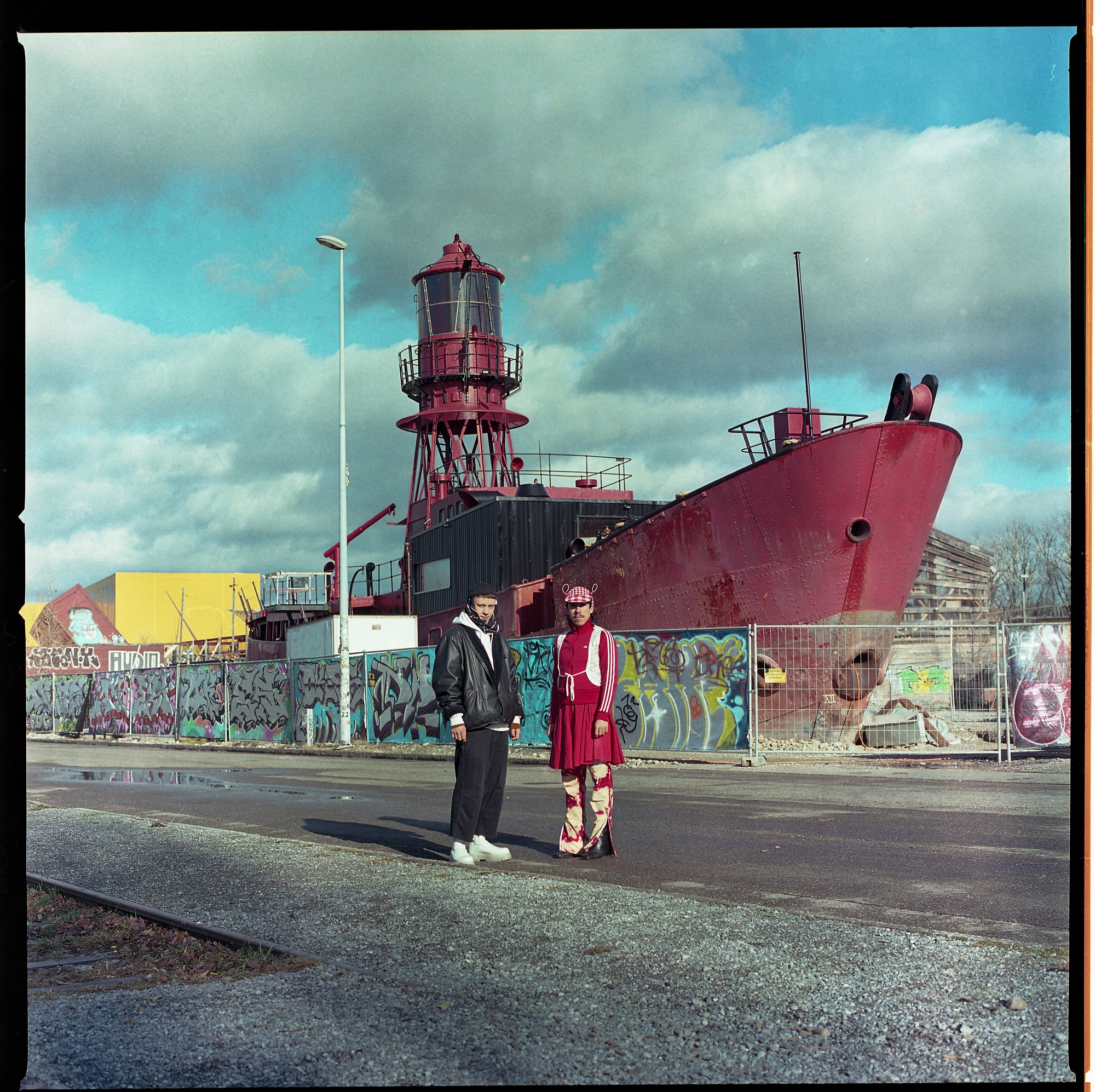 a portrait of two queer swiss people in front of a boat