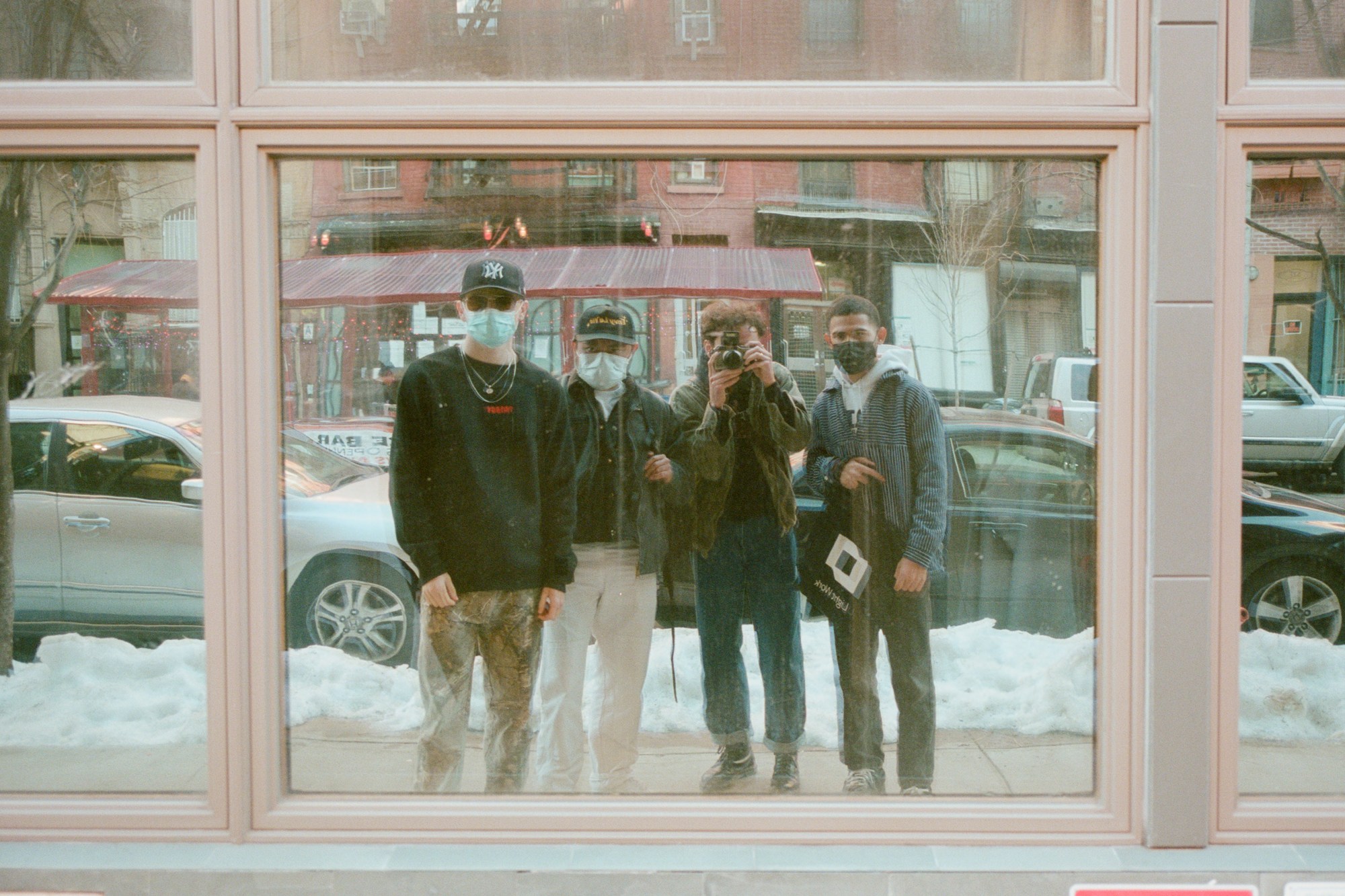 four men in the reflection of a shop front