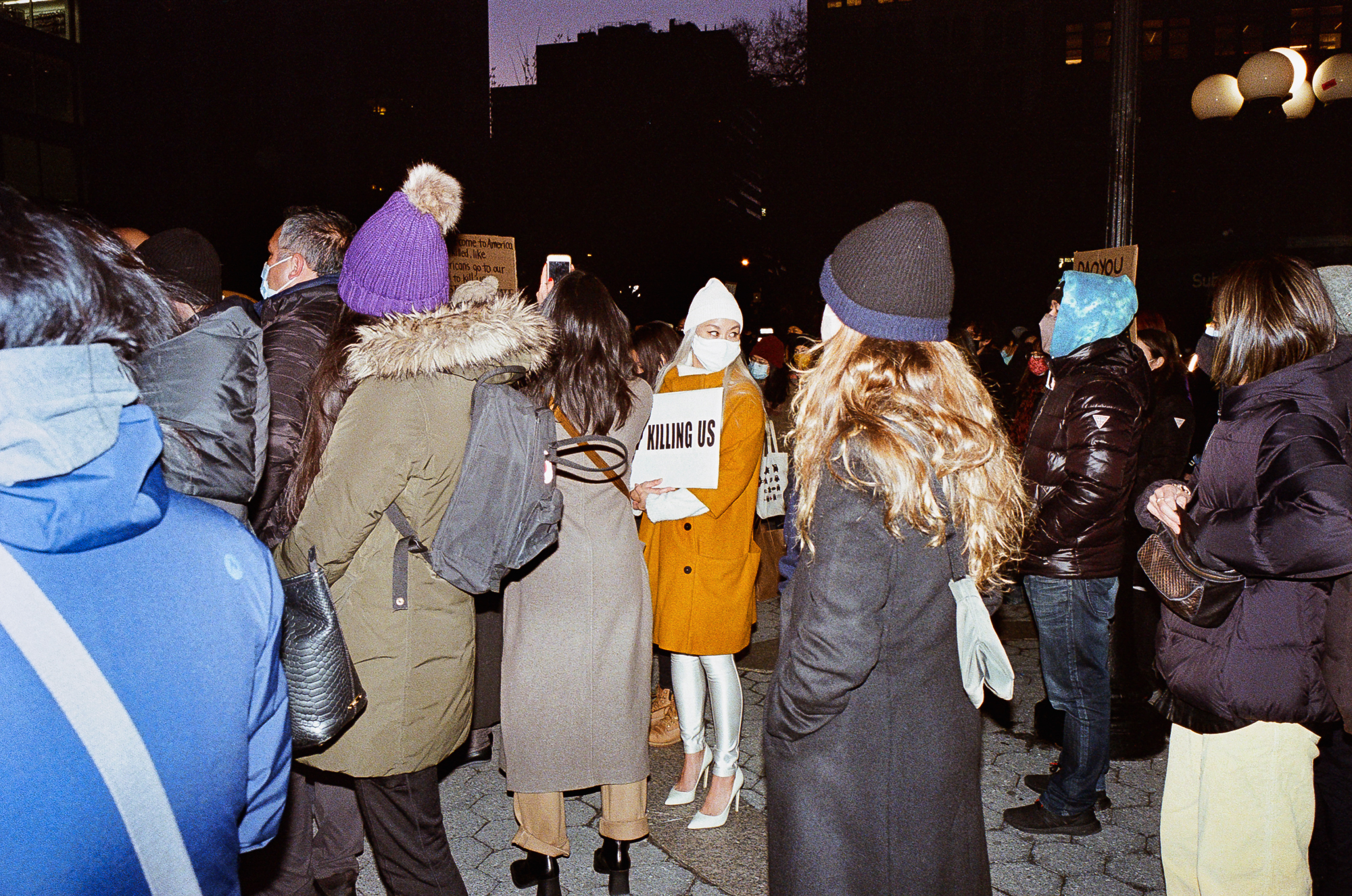 crowds at the asian peace vigil in new york and a woman with a sign that reads 'stop killing us'