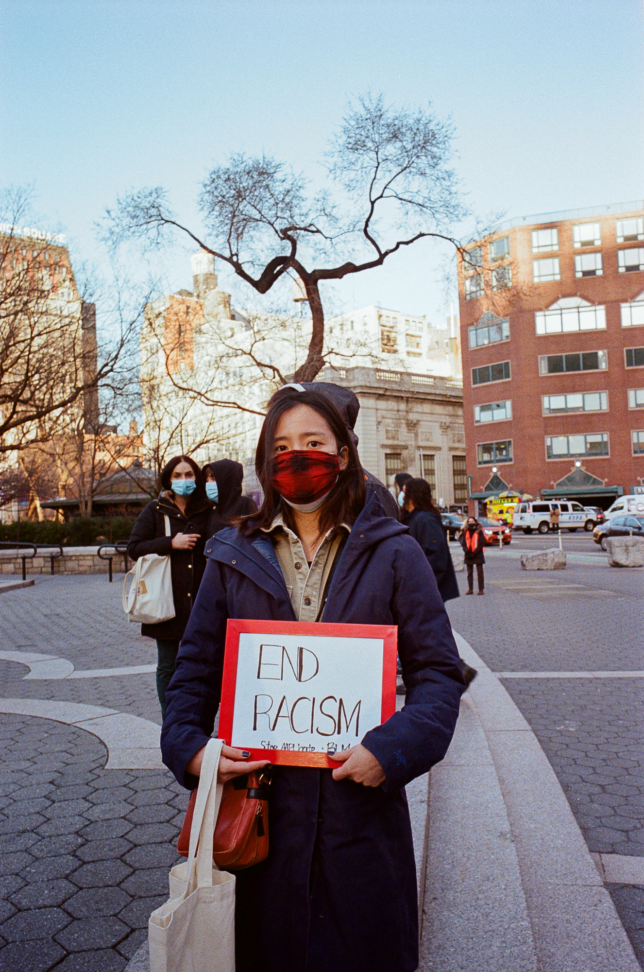 a woman holding a sign that reads end racism, stop aapi hate at the asian peace vigil in new york