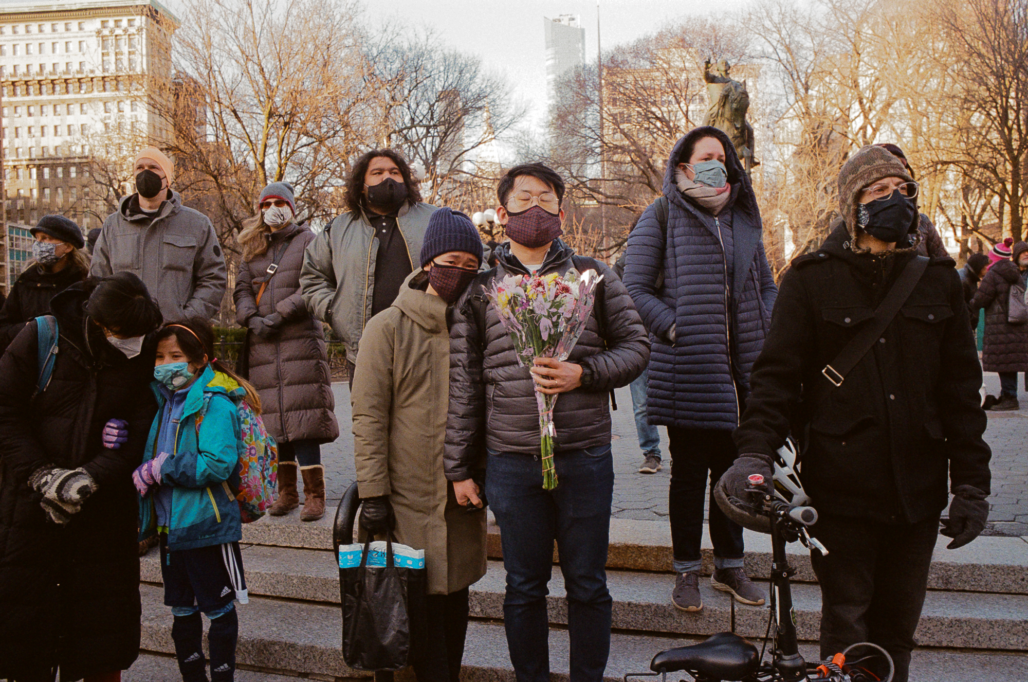 a man holding flowers in a crowd at the asian peace vigil in new york