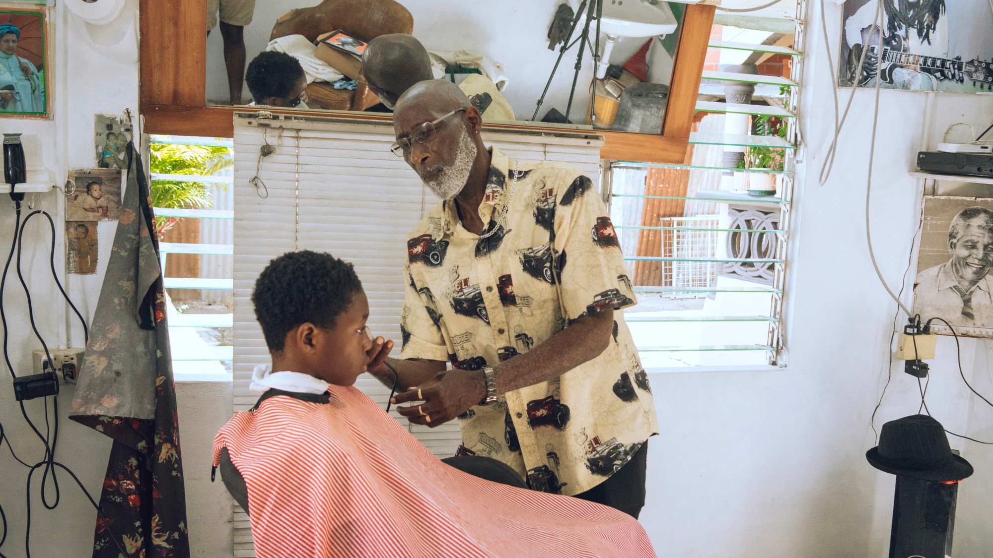 a young boy in a barbers chair as an older man cuts his hair