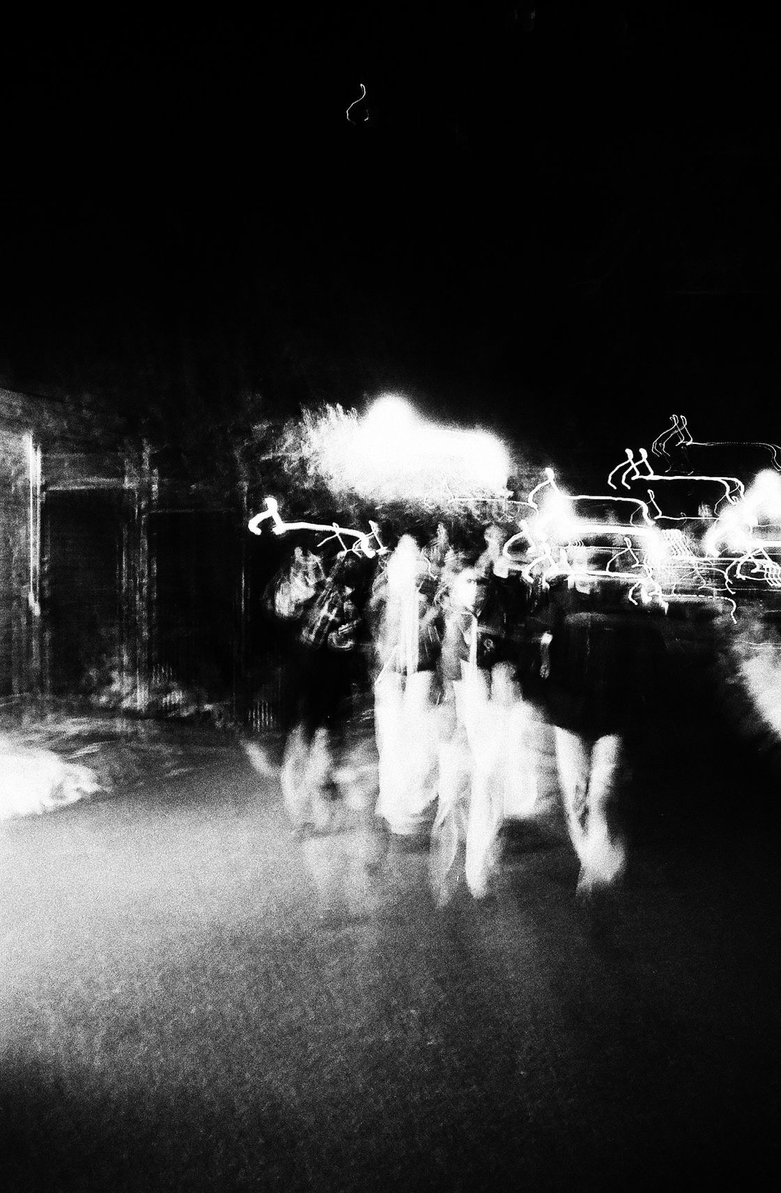 a black-and-white image of blurry lights and people walking at night