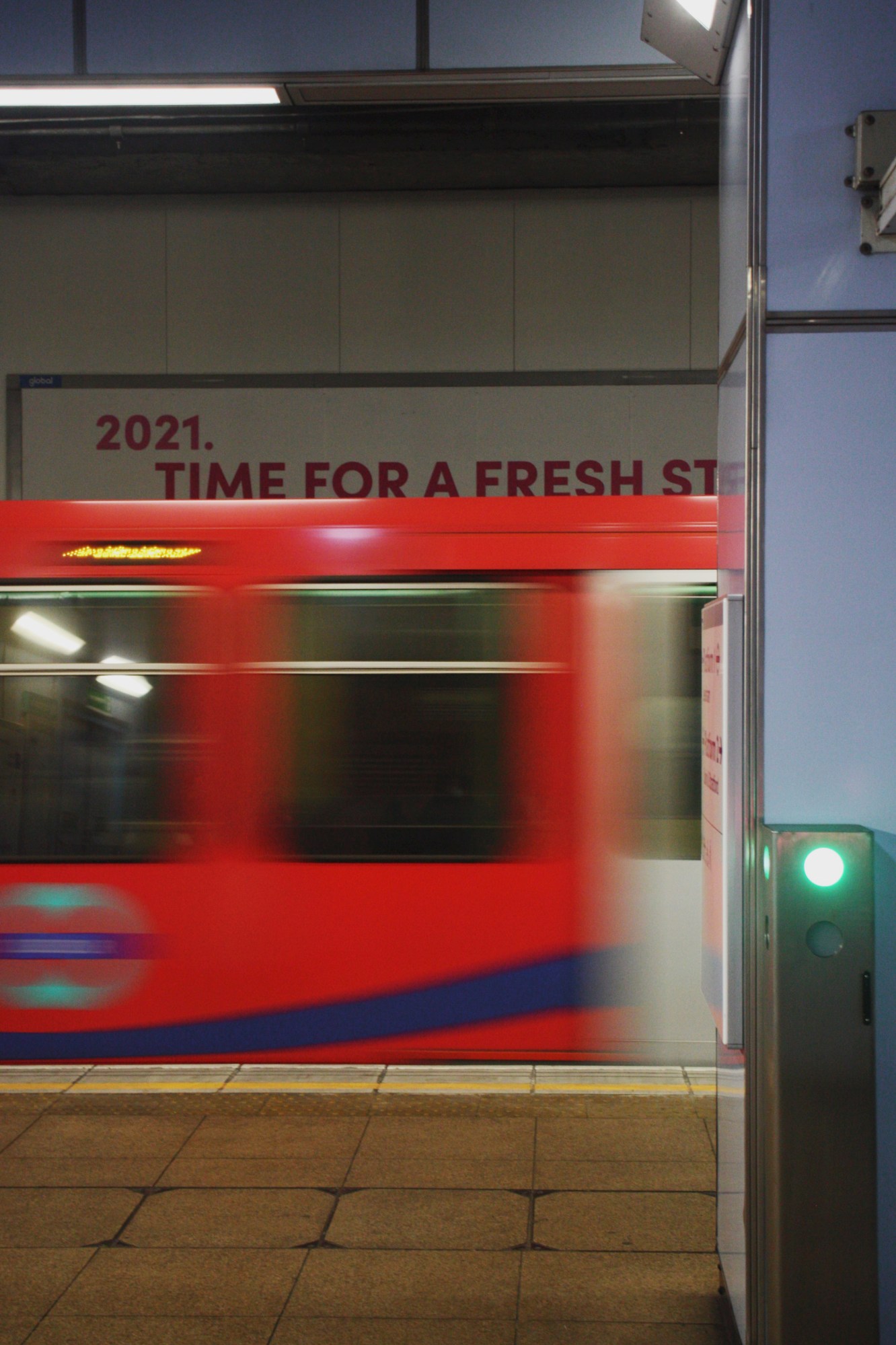 a blurry london underground train pulling into the station, in front of a sign that reads '2021 a fresh start'