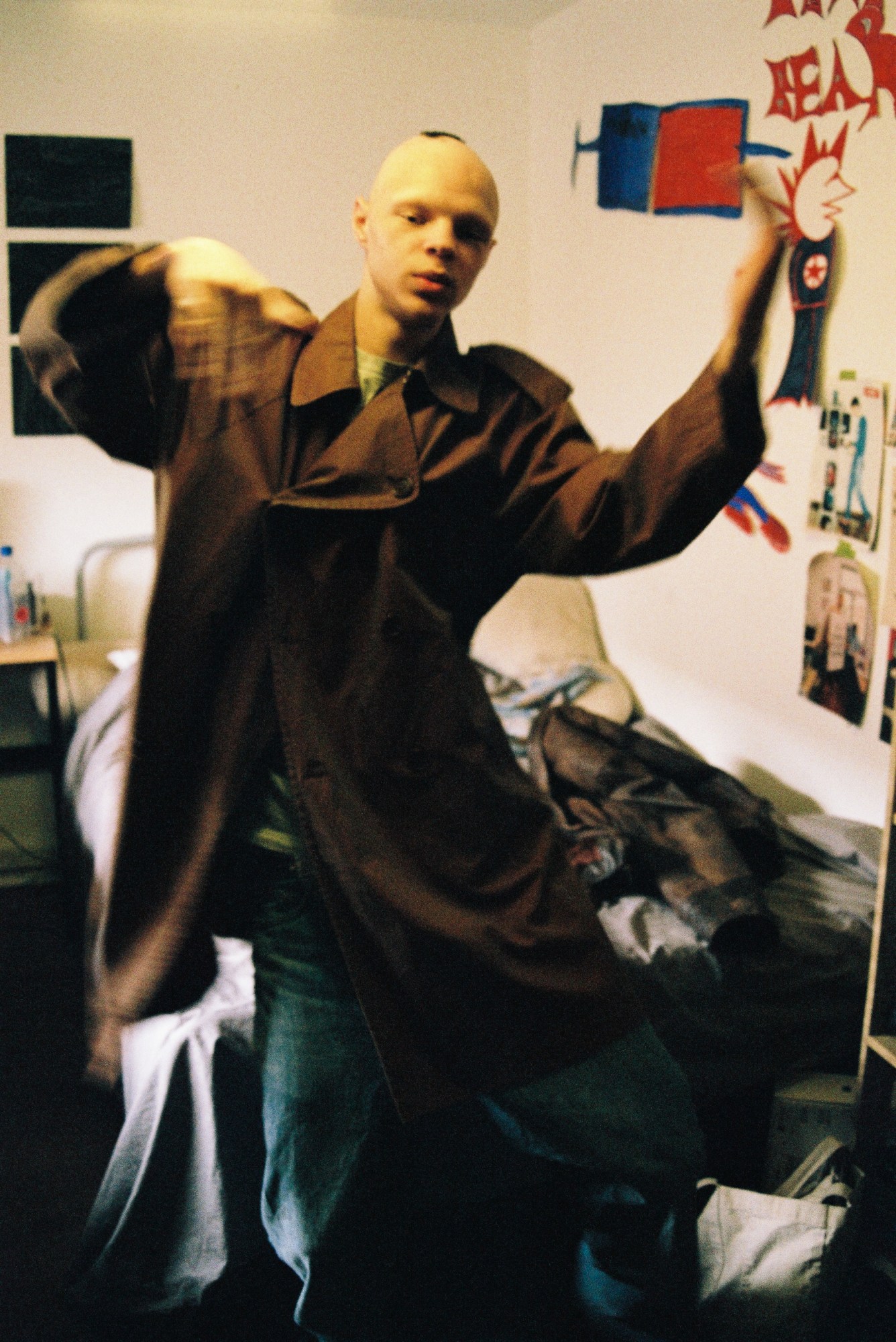 a young man dances in a bedroom with paintings on the walls