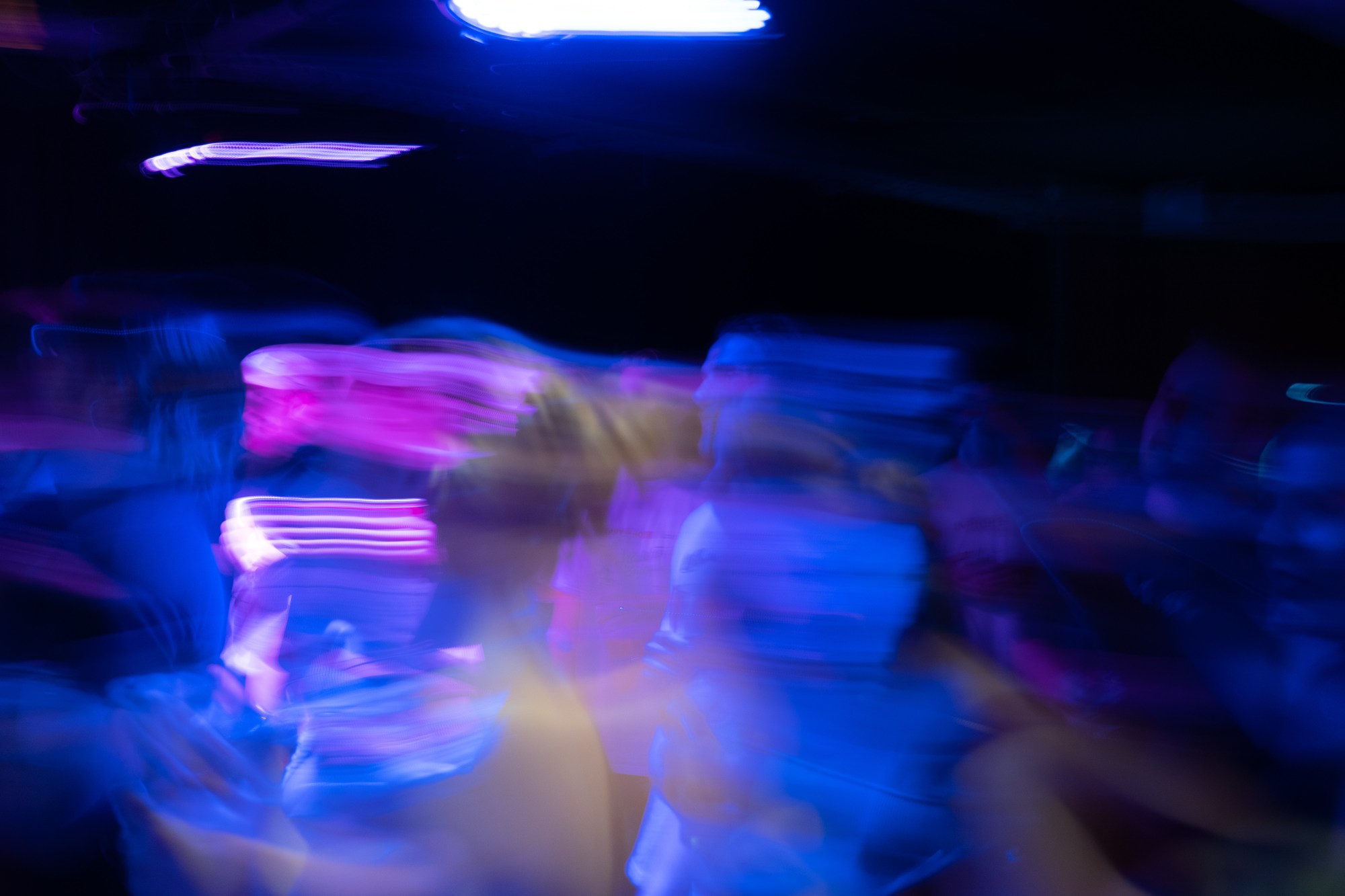 blurry people dancing to music covered in neon blue light