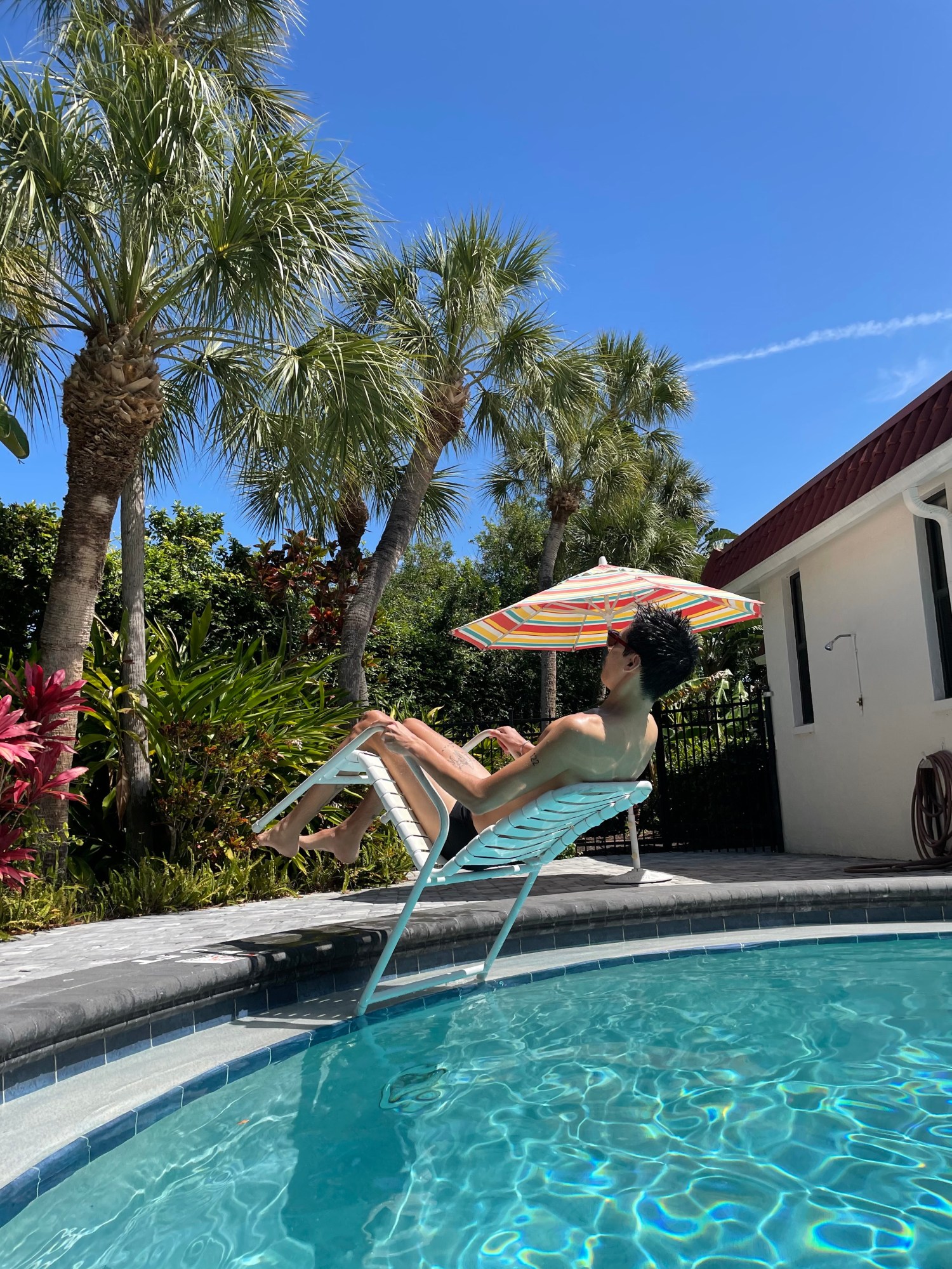 a man sits on a chair that reclines over a swimming pool, unclear as how the chair does this