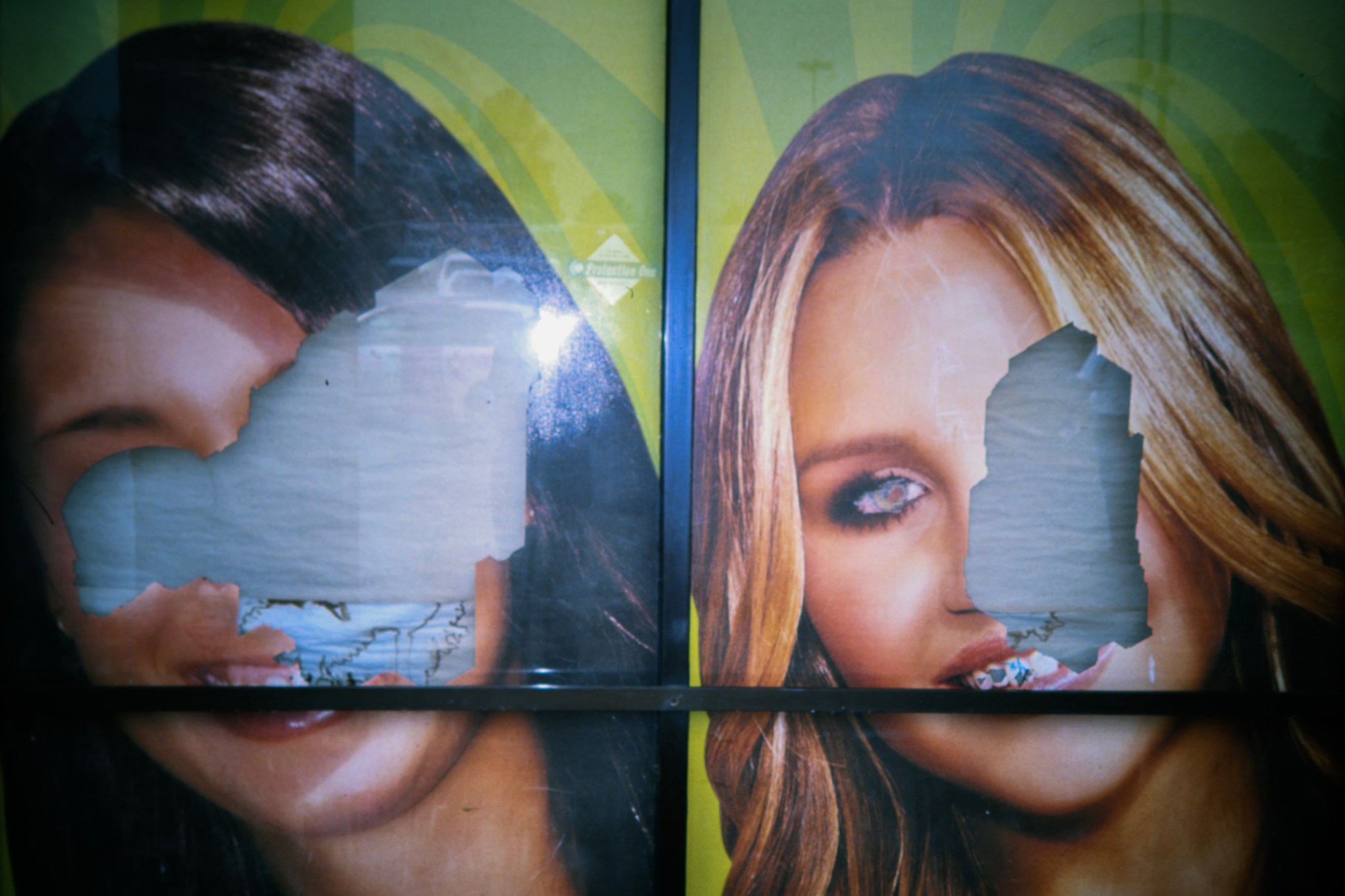 a poster of two celebrities - the one on the right is visibly amanda byrnes - the other has been ripped away