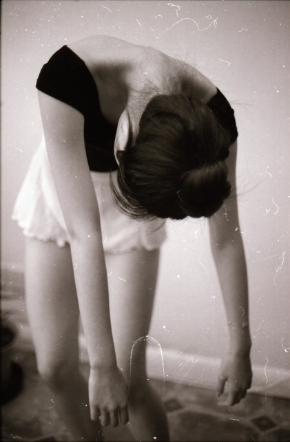 a girl in a ballet outfit hangs her arms and head down