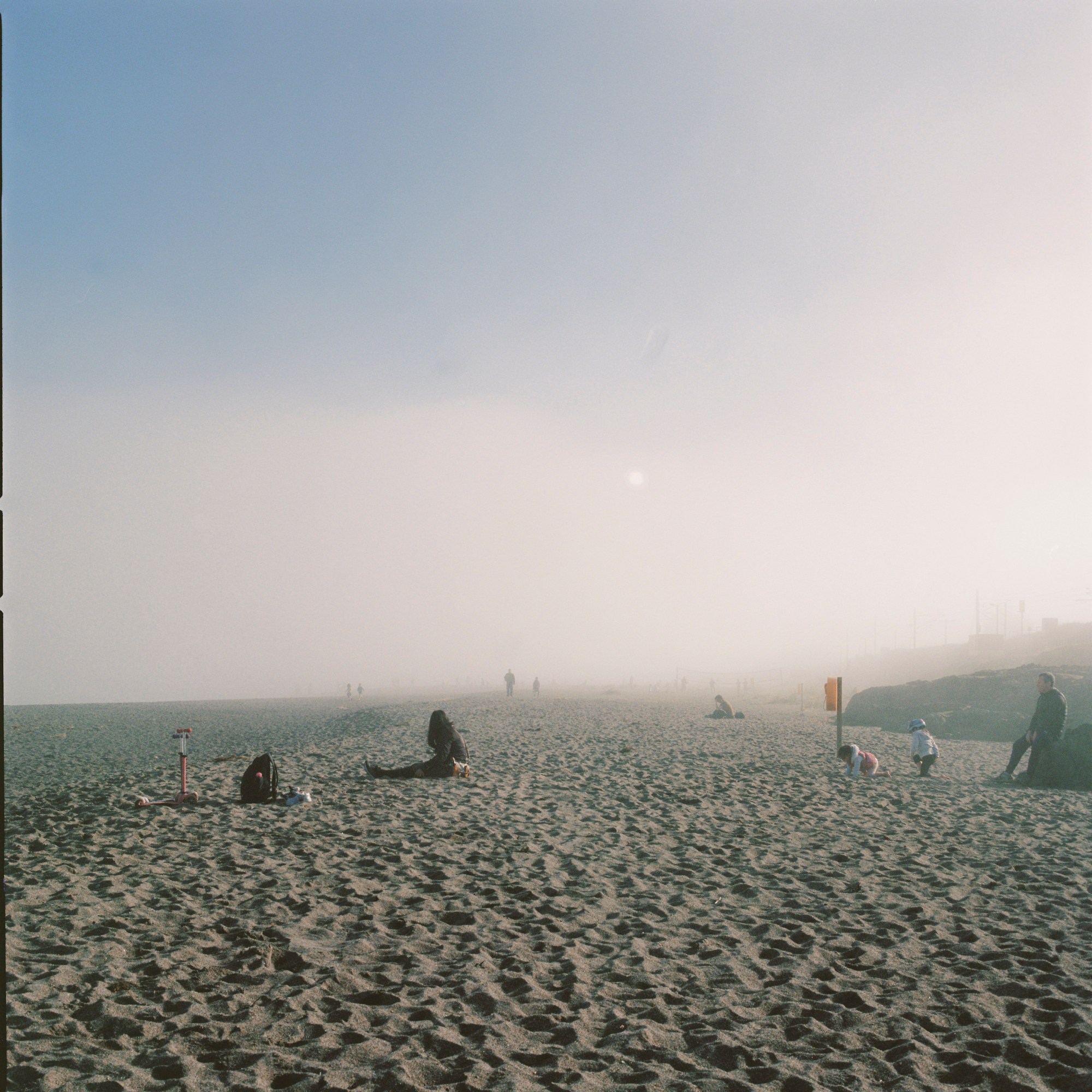 a misty beach with a few people sat down