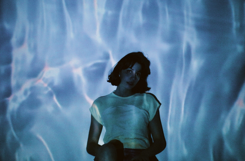 a girl stands up, a projection with a water-like effect across her