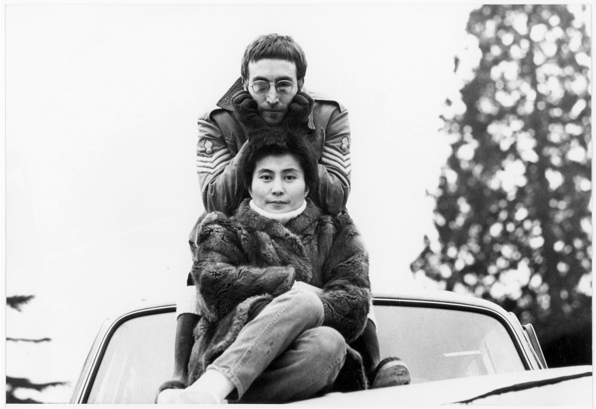 Yoko Ono and John Lennon sitting on top of their crashed car