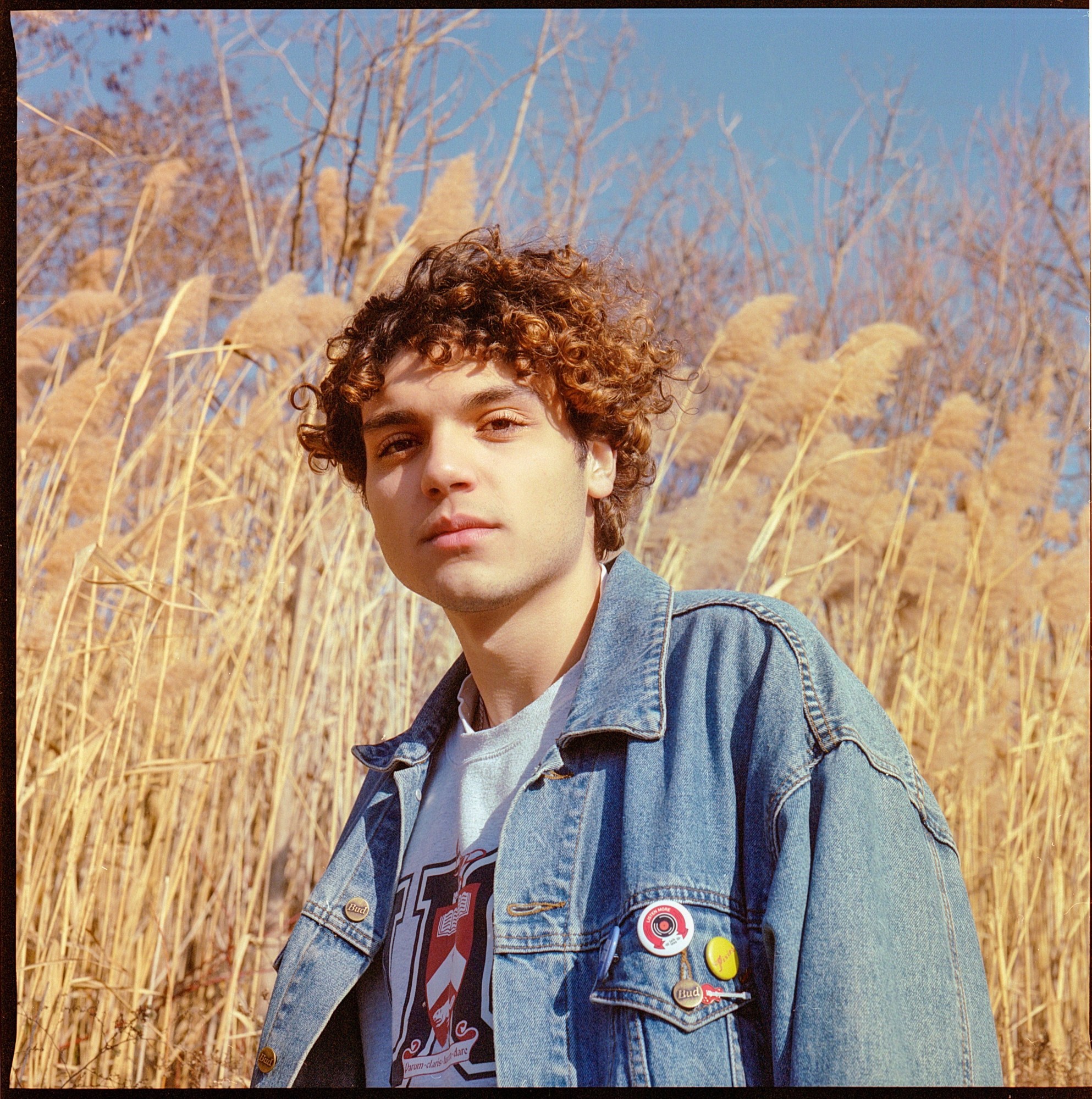 Person in a denim jacket with reeds blowing in the background