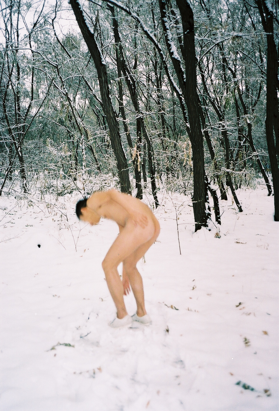 A nude person in a snowy forest clearing