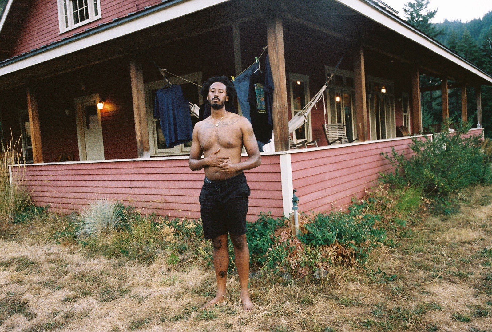 A topless man stood in front of a house.