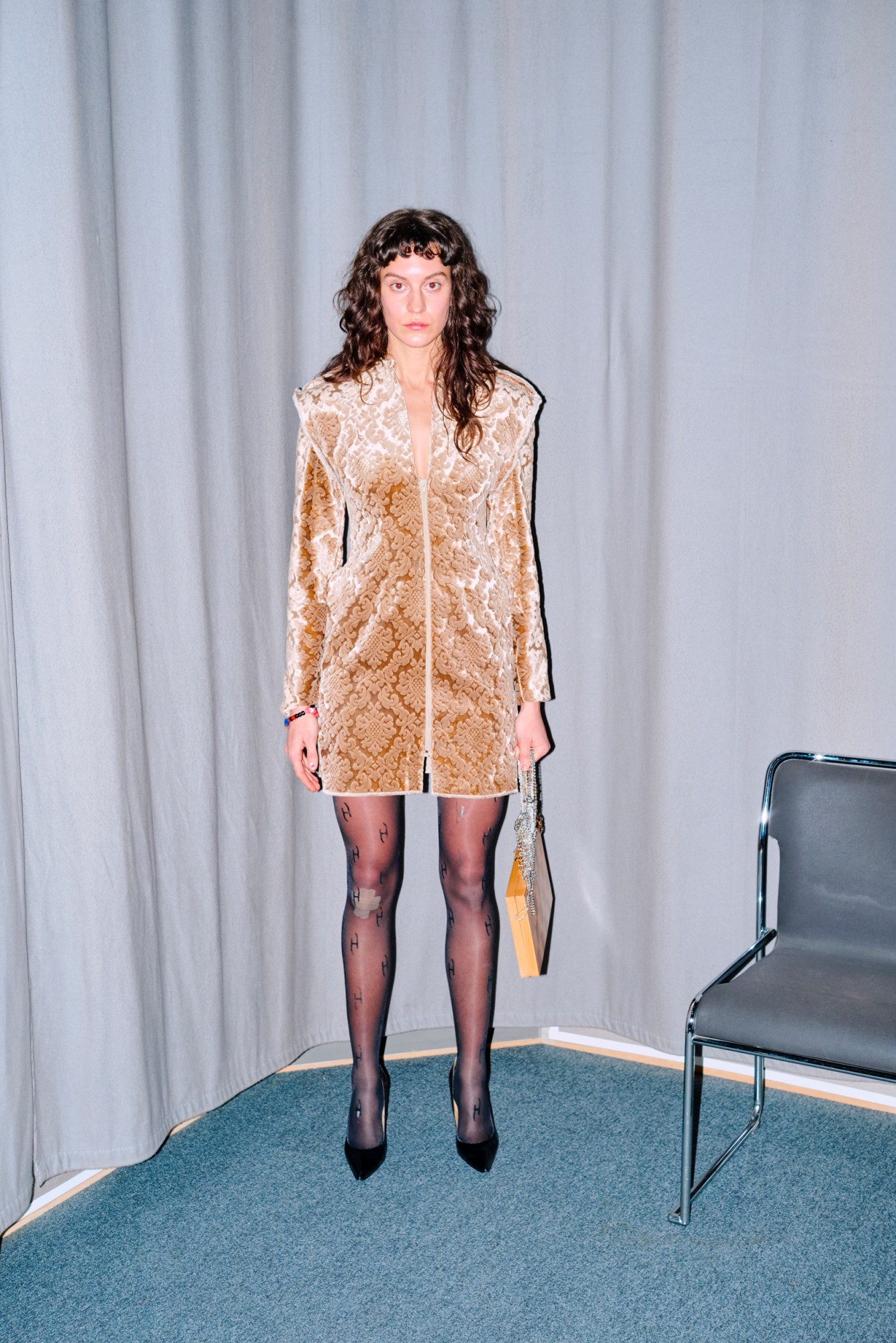 model wearing a gold patterned minidress with strong shoulders, by Ellen Hodakova Larsson