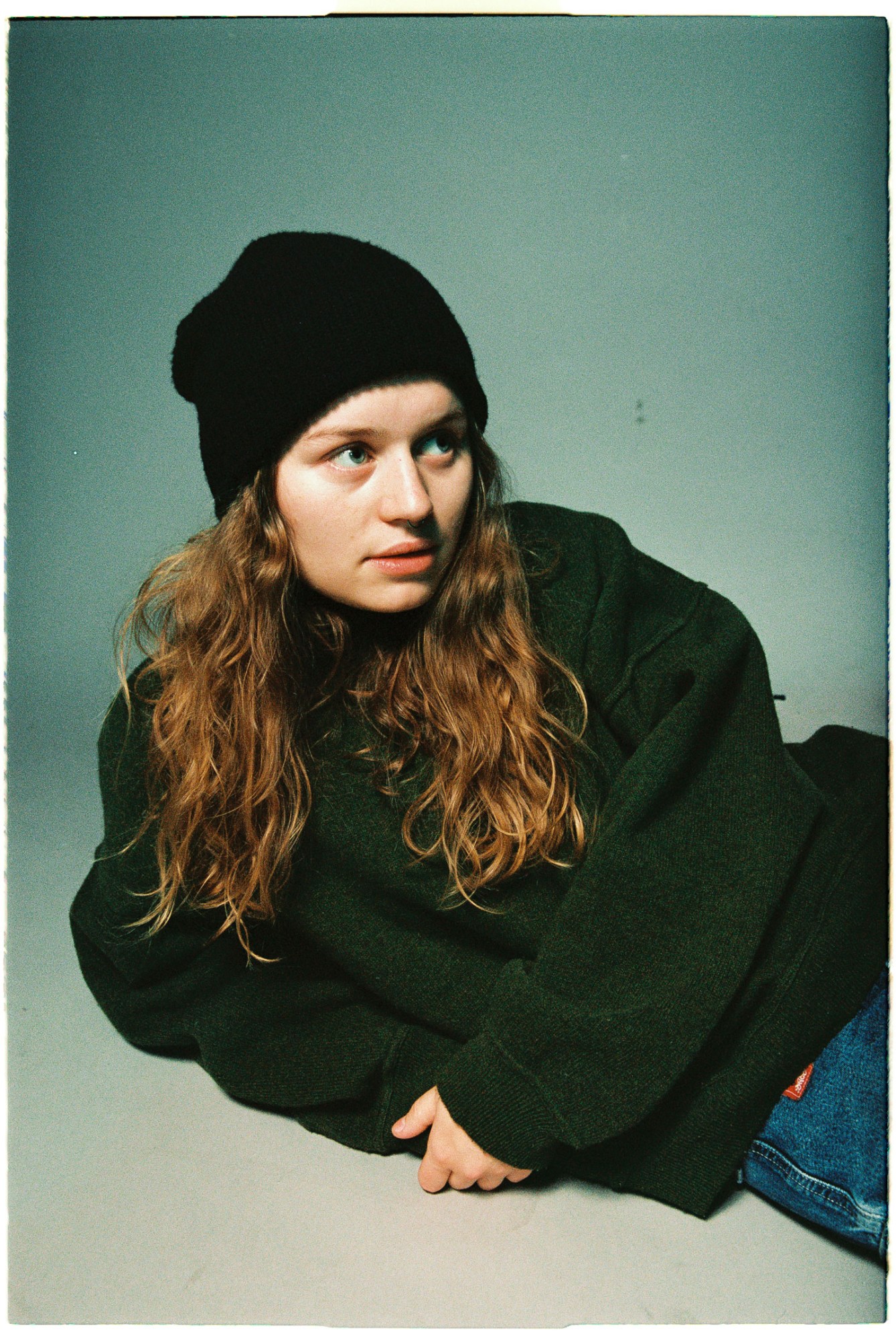 the musician girl in red reclining in a studio wearing jeans