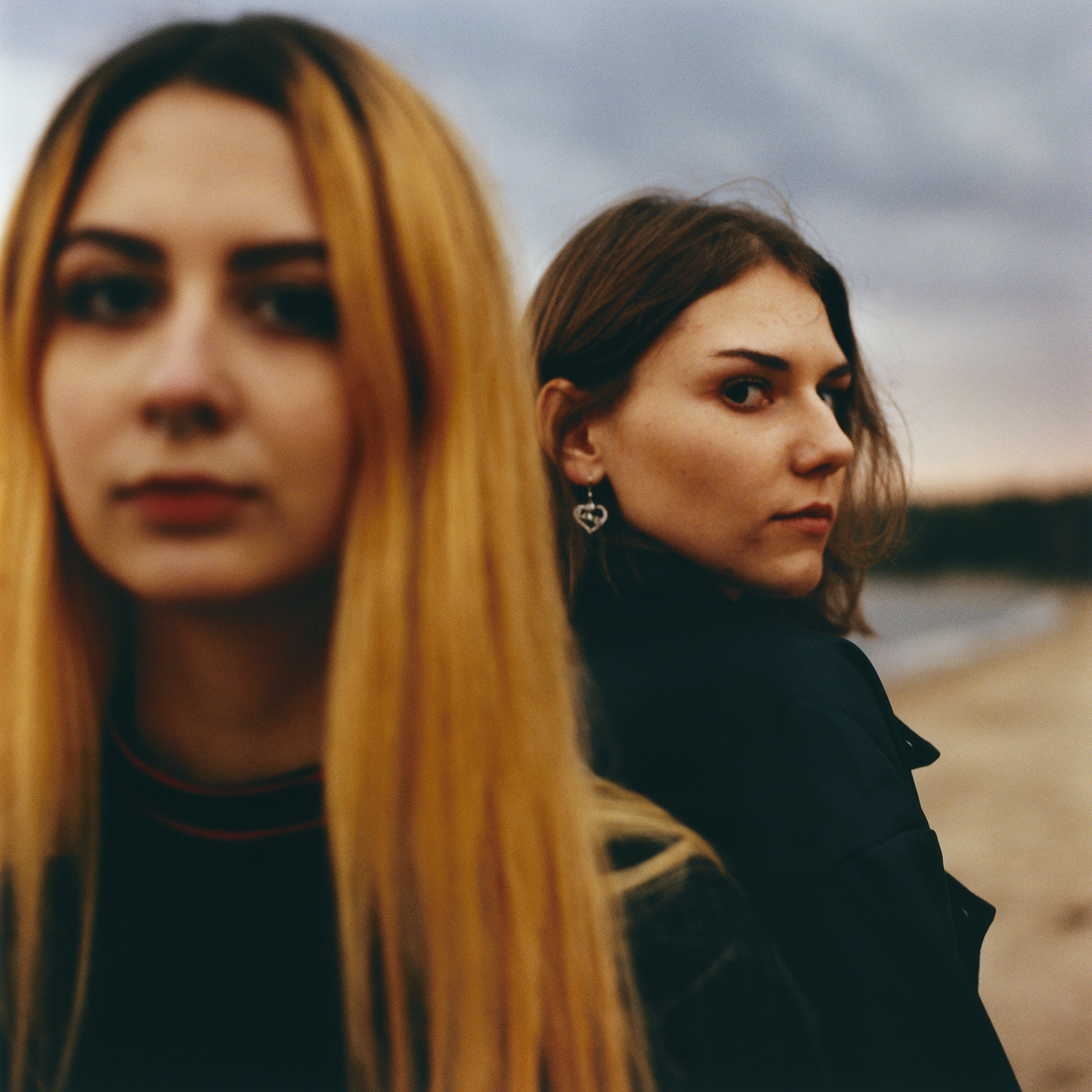 two young women on the beach look into the camera