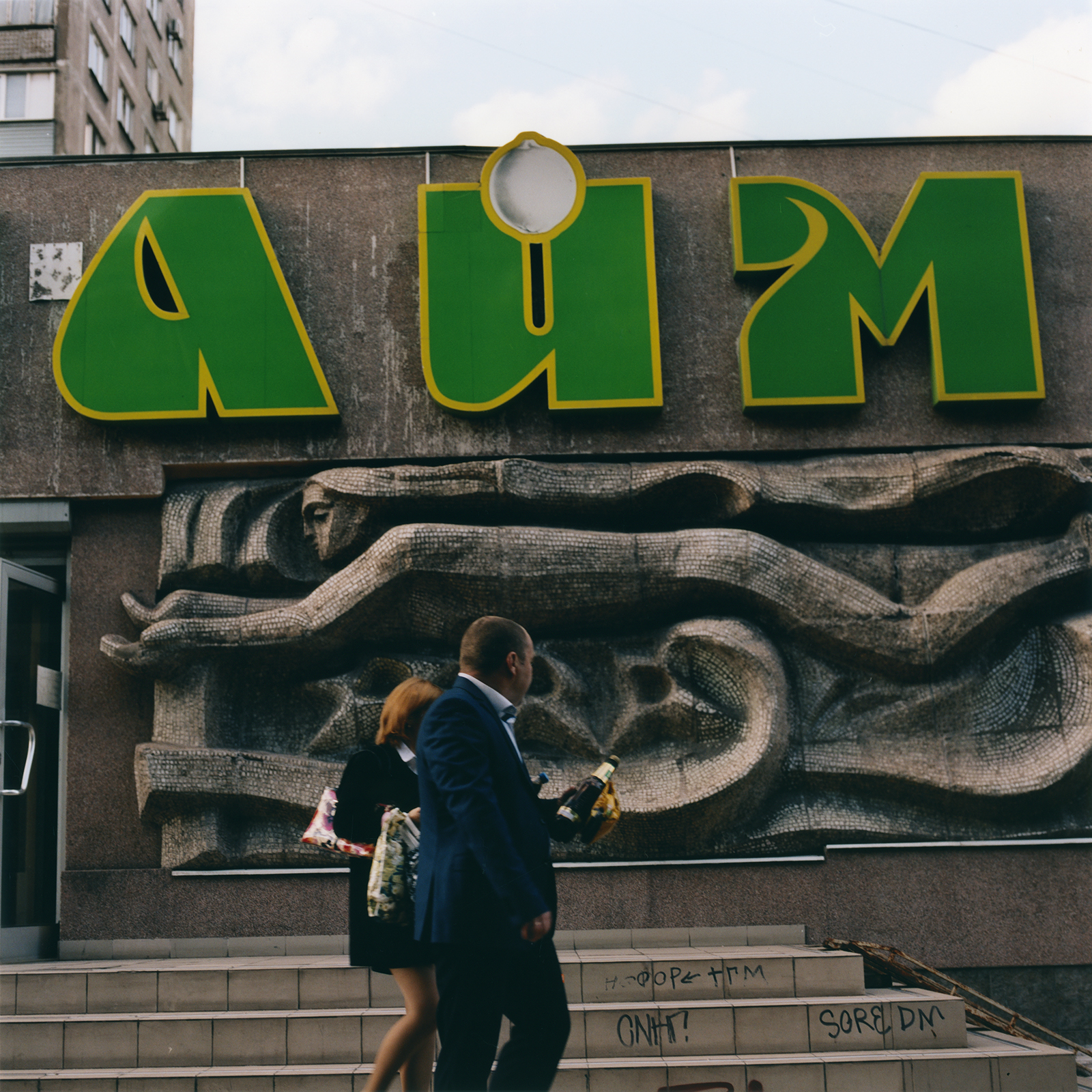 a stone carving inset into a concrete wall, as two people walk past