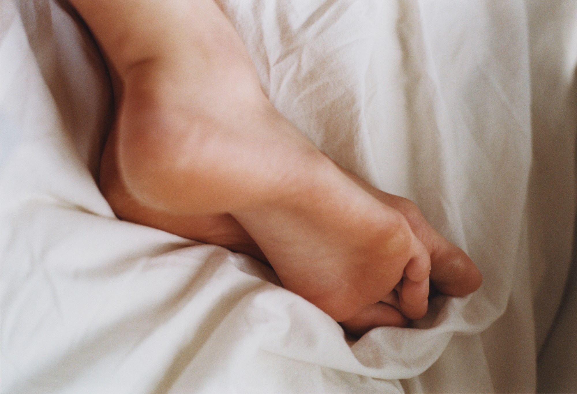 Close up of feet on crumpled sheets