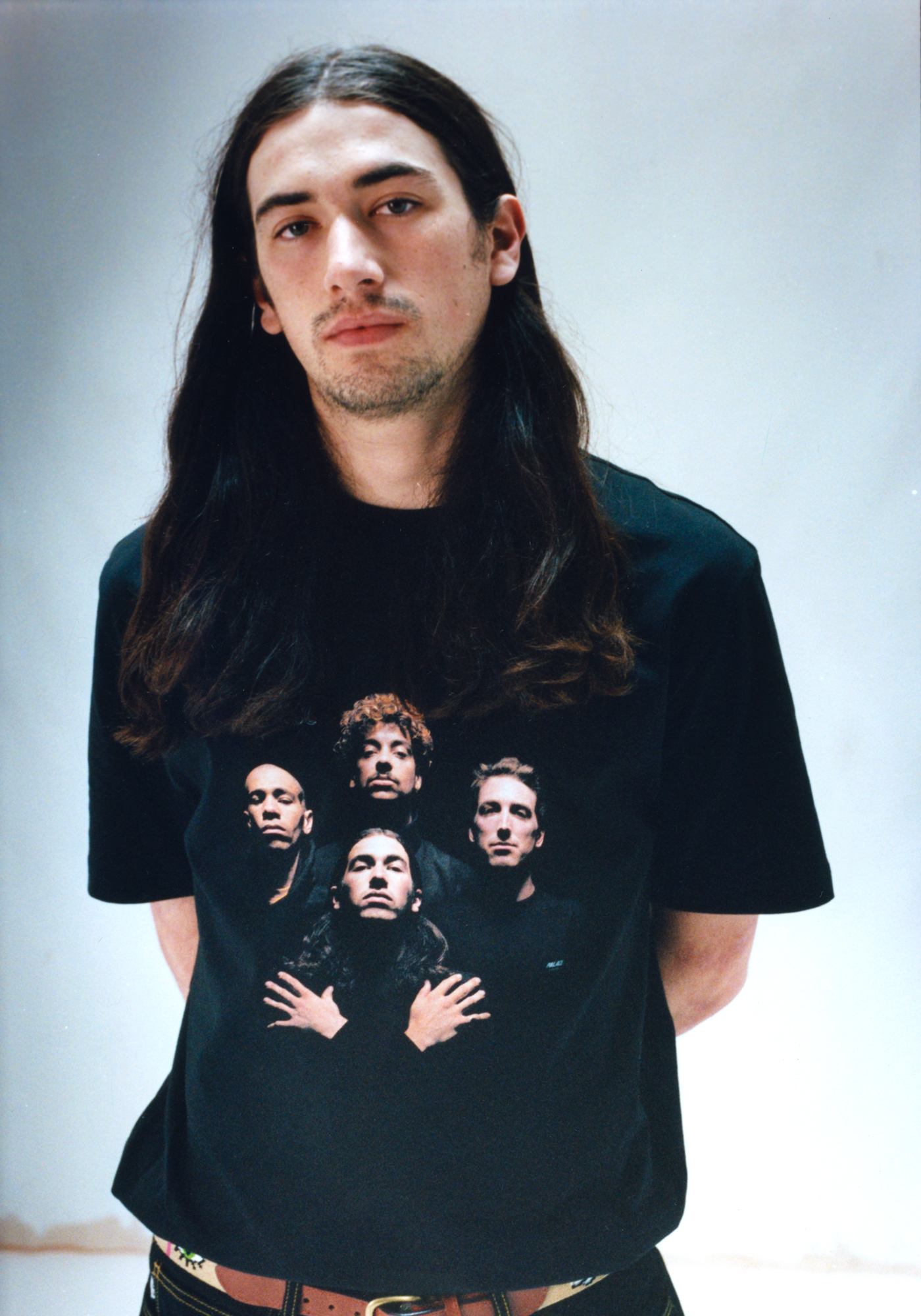 Skater and model Charlie Birch looks to the camera against a white background wearing a Palace t shirt that resembles the Queen Bohemian Rhapsody video